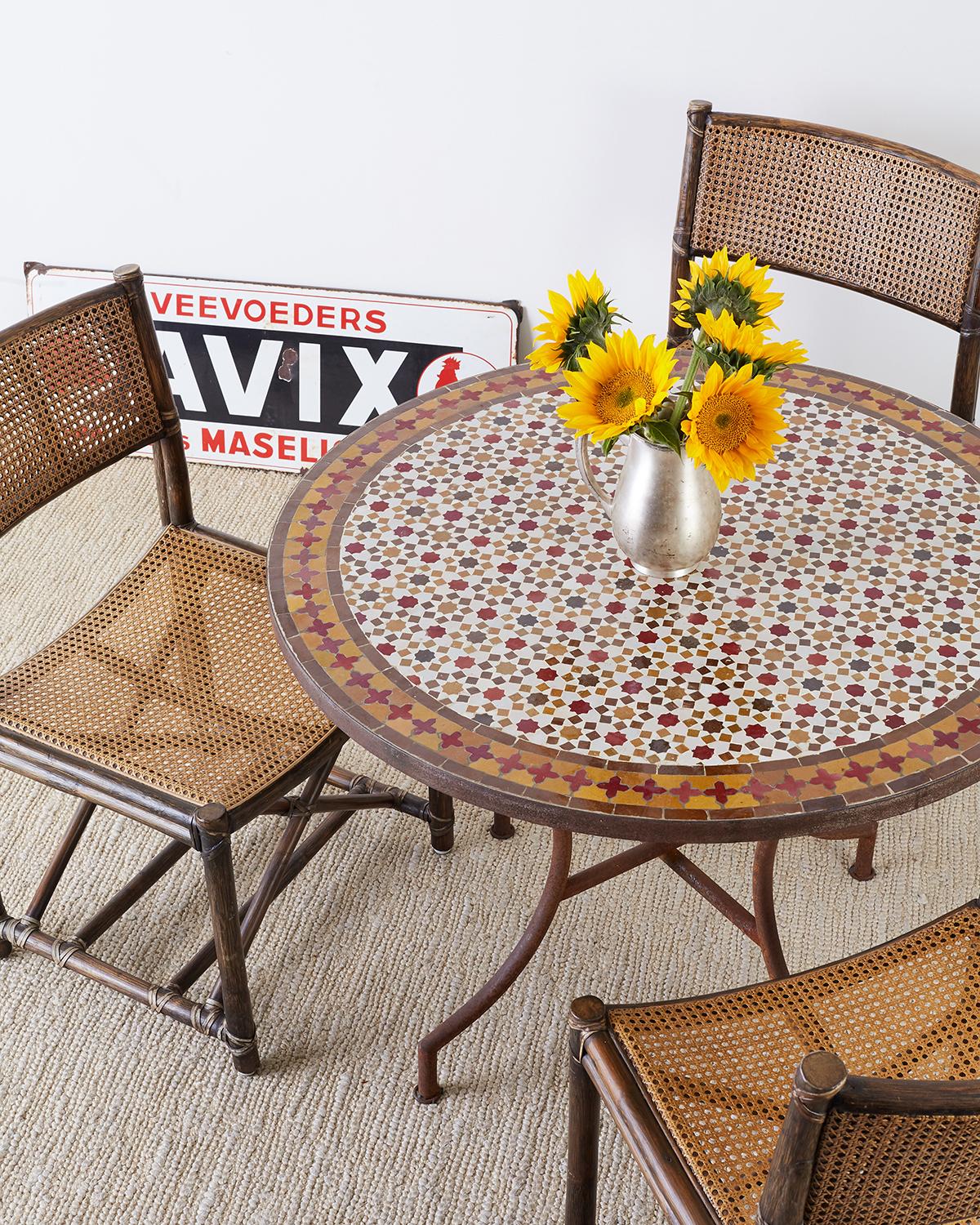 Fantastic Spanish dining table or garden table featuring a round stone top with Moroccan mosaic tile inlay. The intricately detailed tiles consists of octagonal shaped stars surrounded by squares. The border of the table has a darker band with red