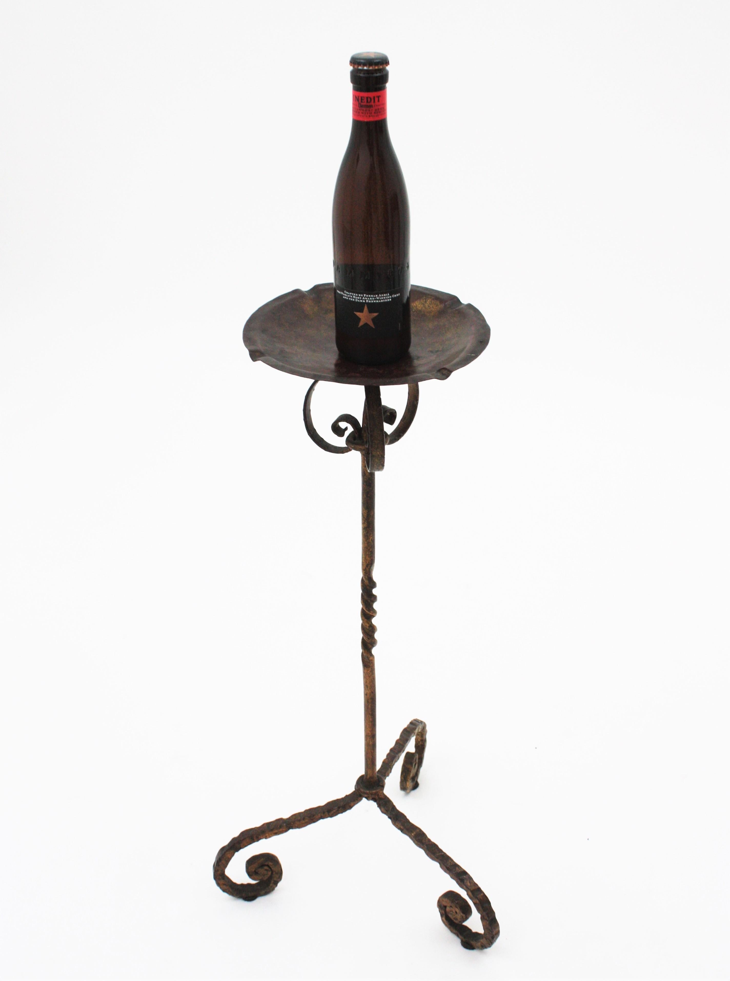 Spanish wrought iron floor ashtray or drinks / cocktails table standing on a tripod base, Spain, 1940s.
Handcrafted in wrought iron. The top stands on a tripod base with twisting details on the stem and scroll endeded feet. Terrific parcel-gilt