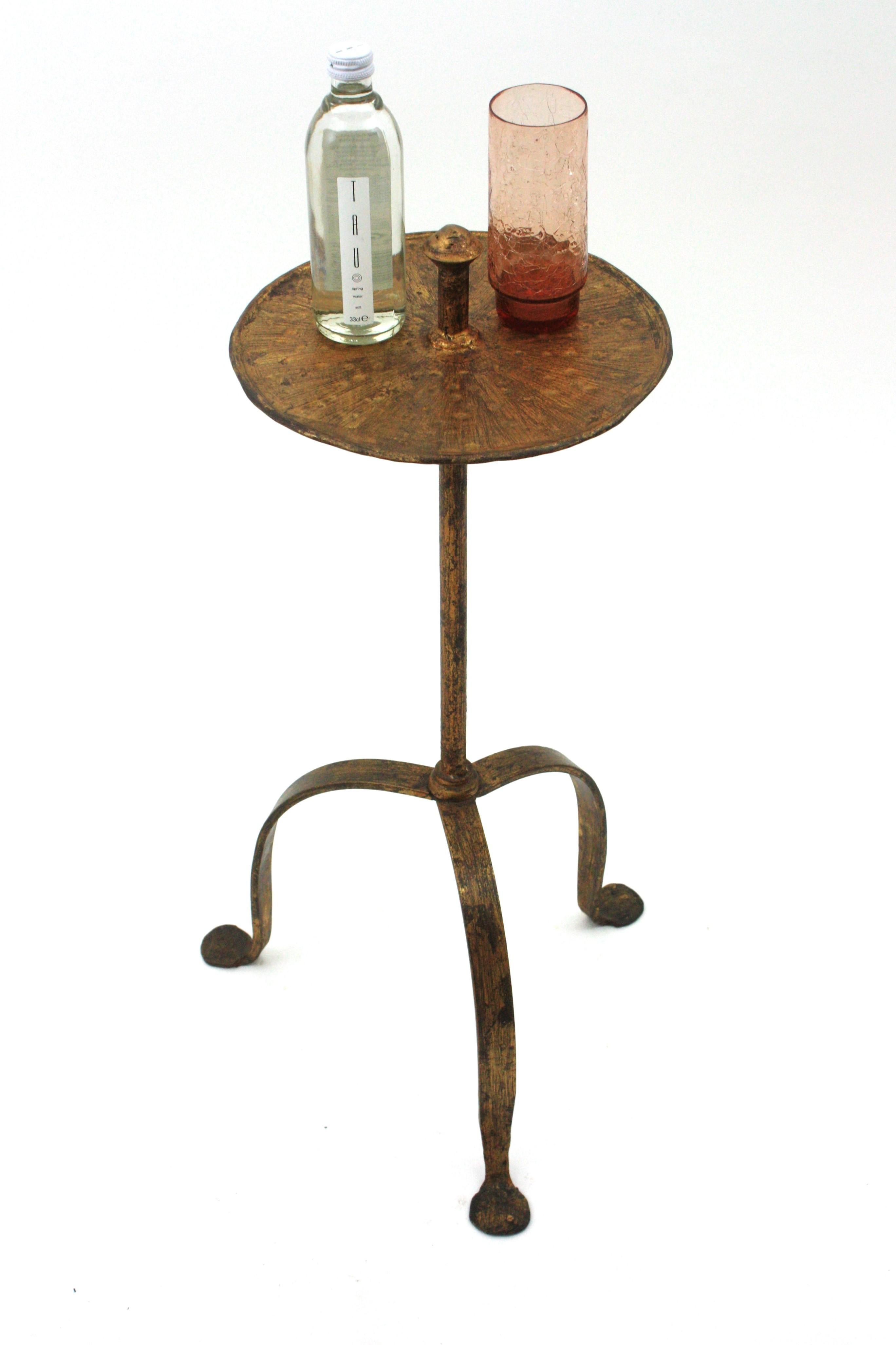 Elegant hand-hammered iron drinks end table or pedestal table standing on a tripod base with handle on the top. Spain, 1940s.
This table features a round top richly adorned by the Hammer marks standing on a tripod base with round ending feet. The