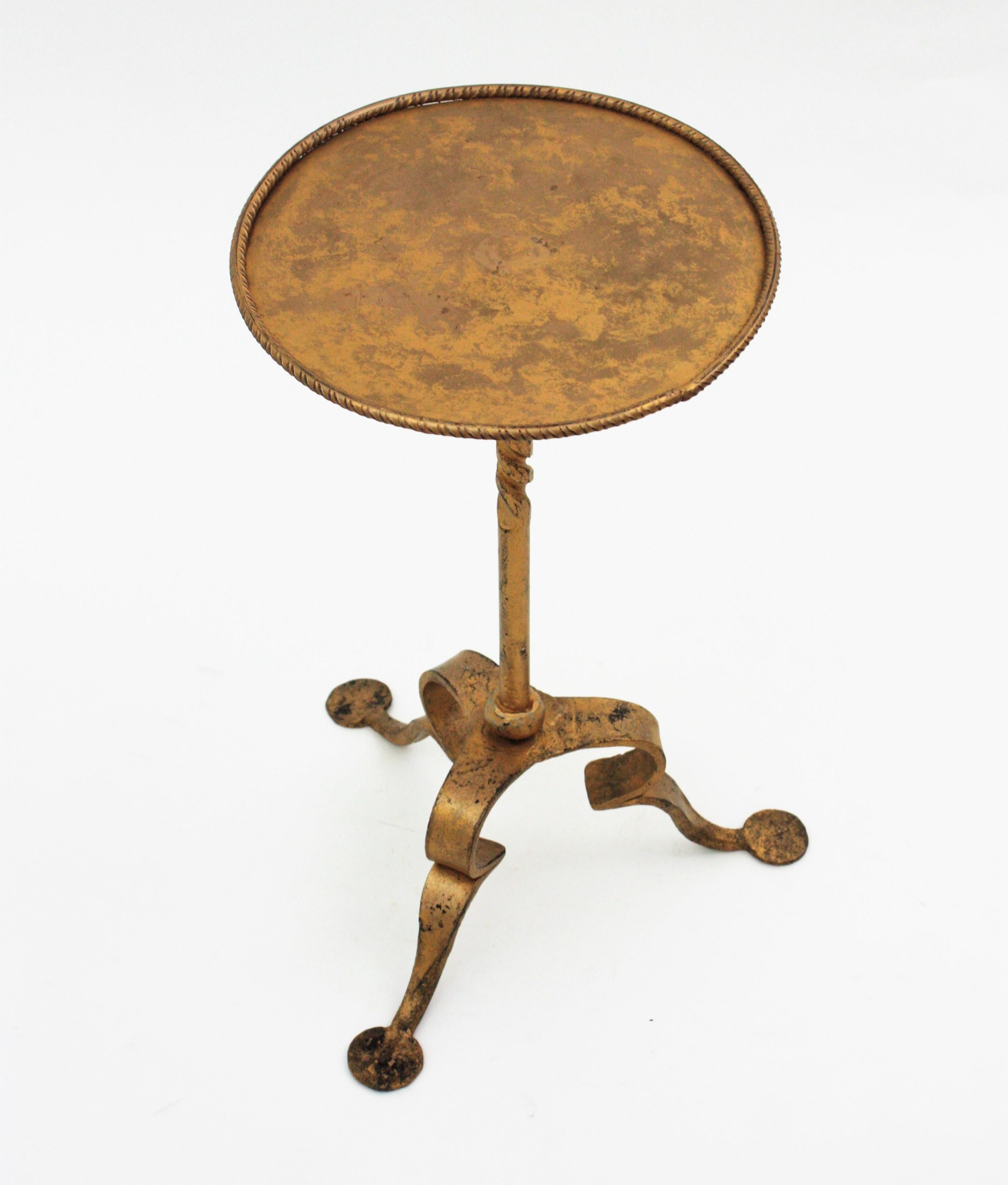 Spanish drinks table on a tripod base, Spain, 1950s
Entirely made in hand forged iron, gilt finish.
It has a clean design with Gothic style accents. The round top has a small rim, it stands on a tripod base and it has a ring decoration at the