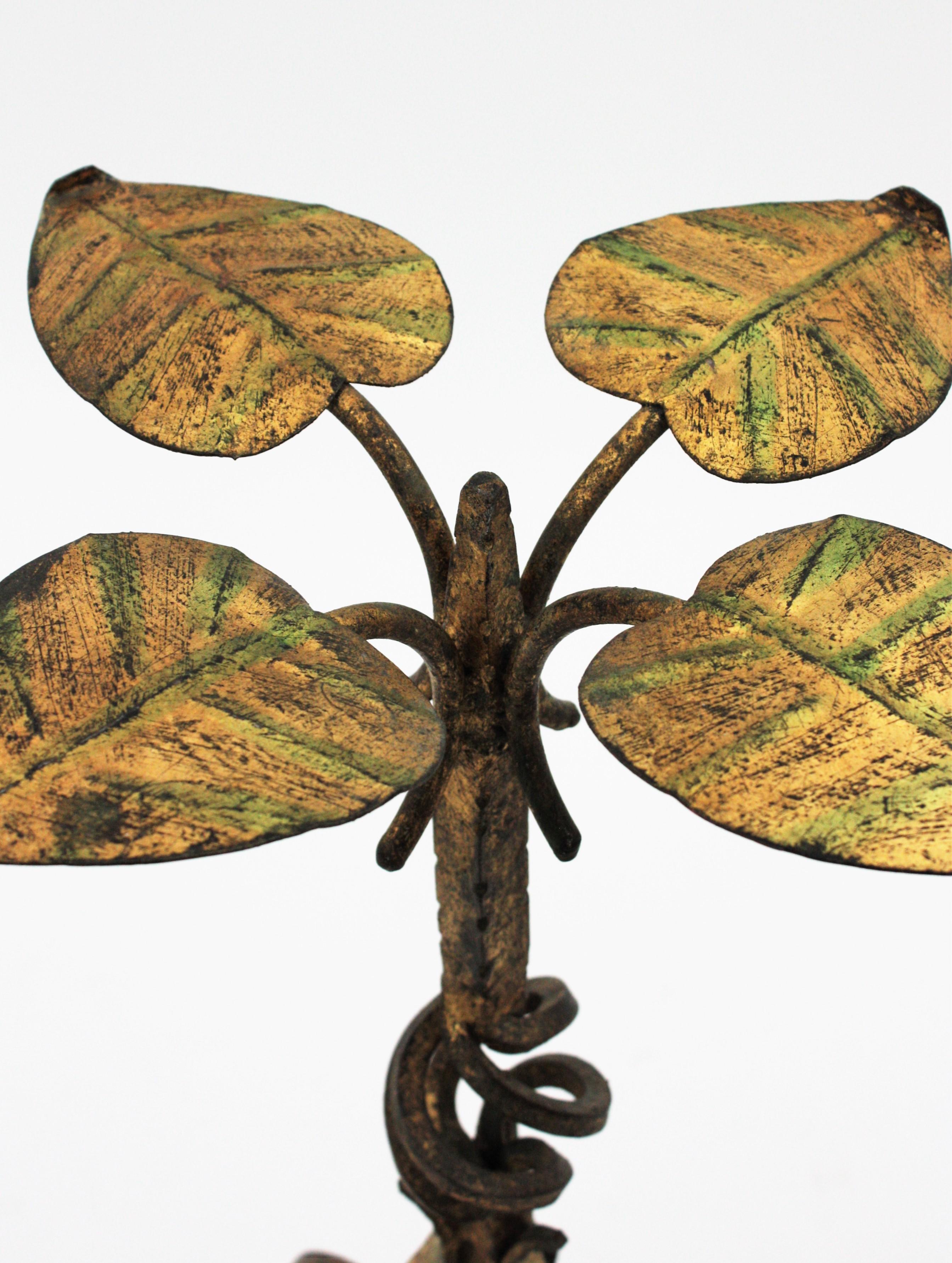 Eye-catching Hollywood Regency gilt iron gueridon drinks table with foliage detailed top. Spain, 1940s.
This beautiful hand wrought iron round table stands up on three legs with. It has beautiful decorative details at the stem and a top made of