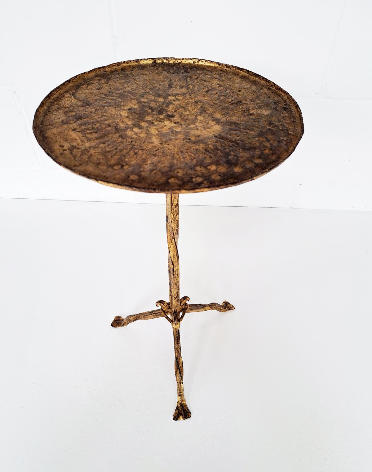 Beautiful hand-hammered gilt wrought iron occasional drinks table on a tripod base, Spain, 1950s. Entirely made of hand-forged iron. Original gold leaf gilding and a beautiful patina it has a clean design inspired by the Gothic style. The plateau