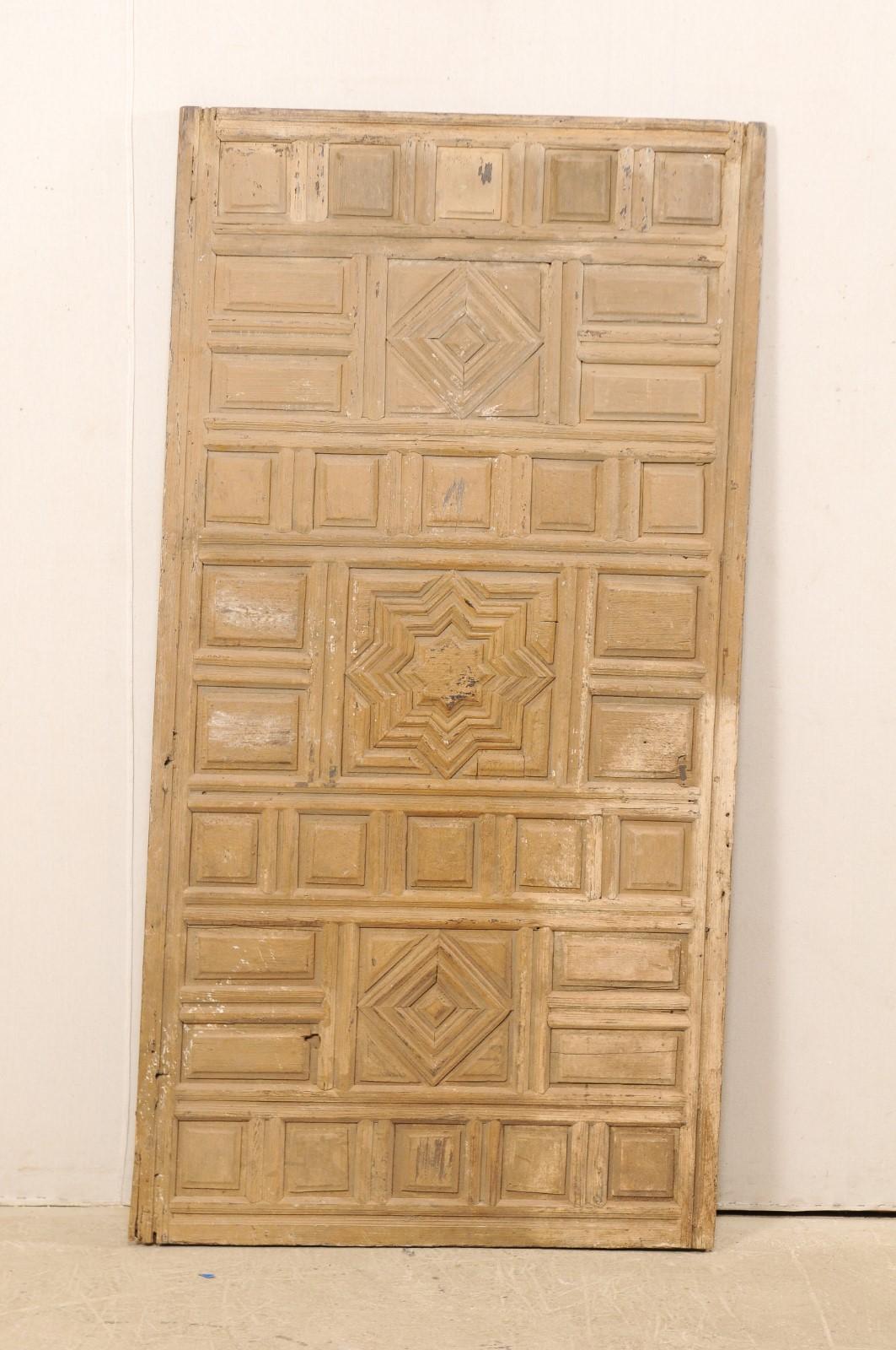 A single Spanish carved-wood wall panel from the early 19th century. This antique wall decoration from Spain features a raised panel front comprised of varying geometric shapes, with a Moorish influence star at center. There is a nicely aged patina