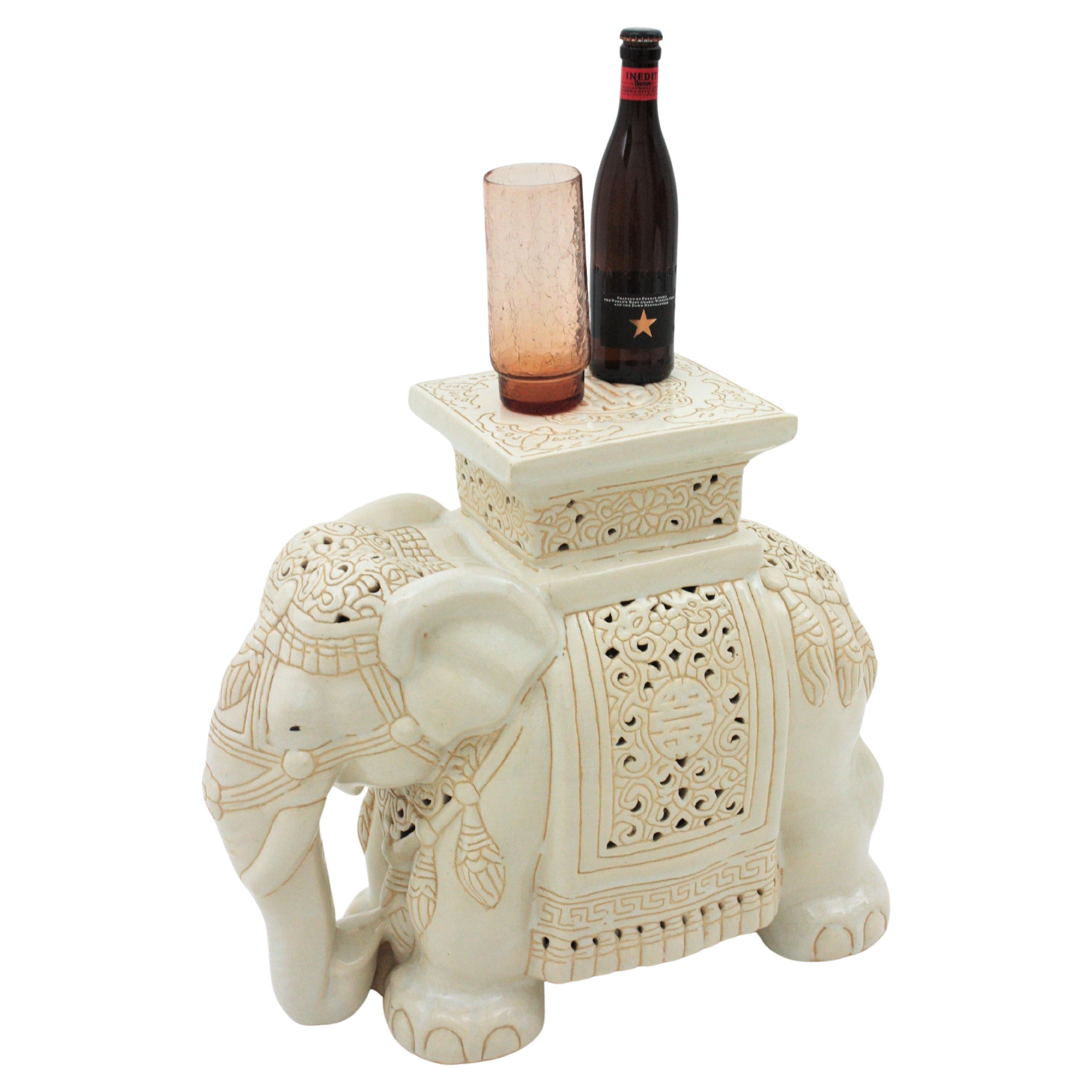 Eye-catching elephant table in off-white glazed ceramic.  Spain, 1960s
This elephant shaped end table stand was beautifully constructed. Its design combines Colonial Revival and Hollywood Regency accents.
It can be used as drinks table, end or side