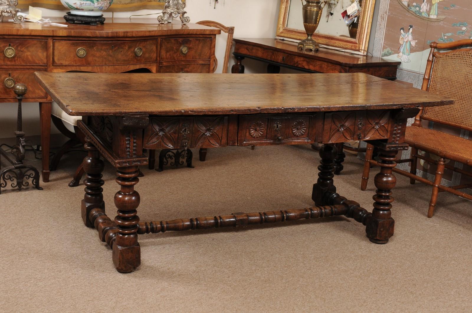 A Spanish baroque refractory table in elm with long one piece rectangular top, carved 3 drawers supported by turned legs and stretcher. The table finished on all sides.