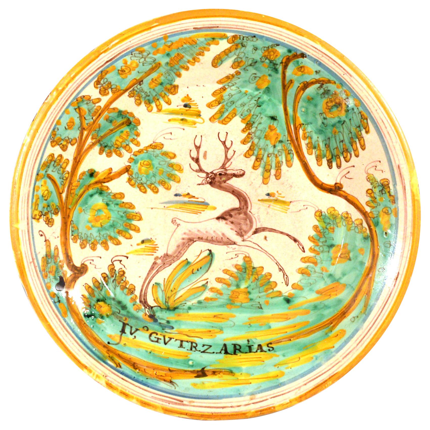 Spanish Faience charger with leaping stag,
Talavera,
circa 1780-1800

The large deep tin-glazed earthenware dish is painted with a large figure of a stylized prancing stag amongst oak trees. Below is a painted inscription reading 