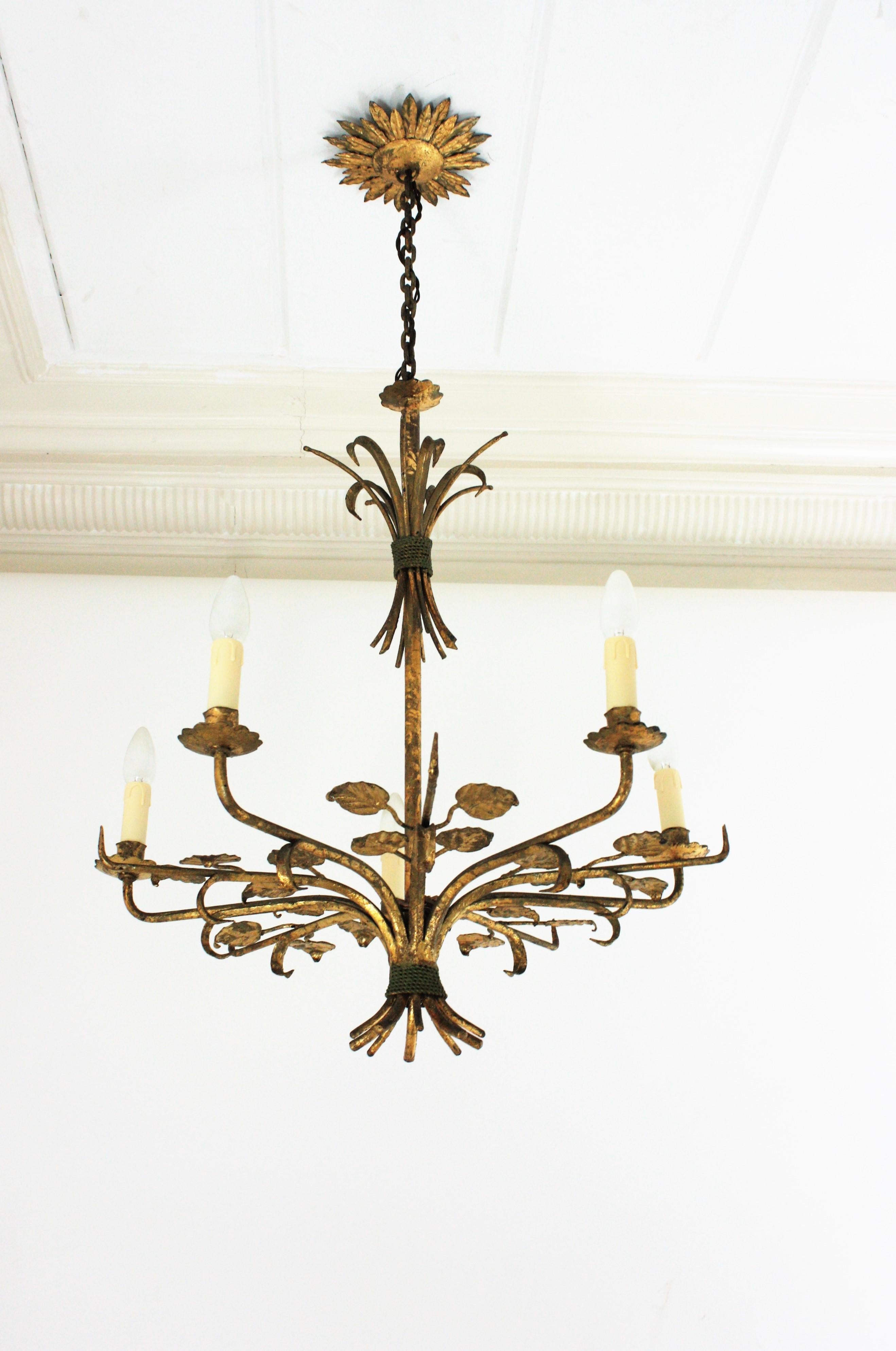 Foliage Chandelier with 5 arms, Gold Leaf, Wrought Iron, Spain, 1940s.
This stunning Hollywood Regency chandelier is entirely made by hand. It has a gilt wrought iron structure with 5 arms as branches in star shape or sunburst disposition. It has
