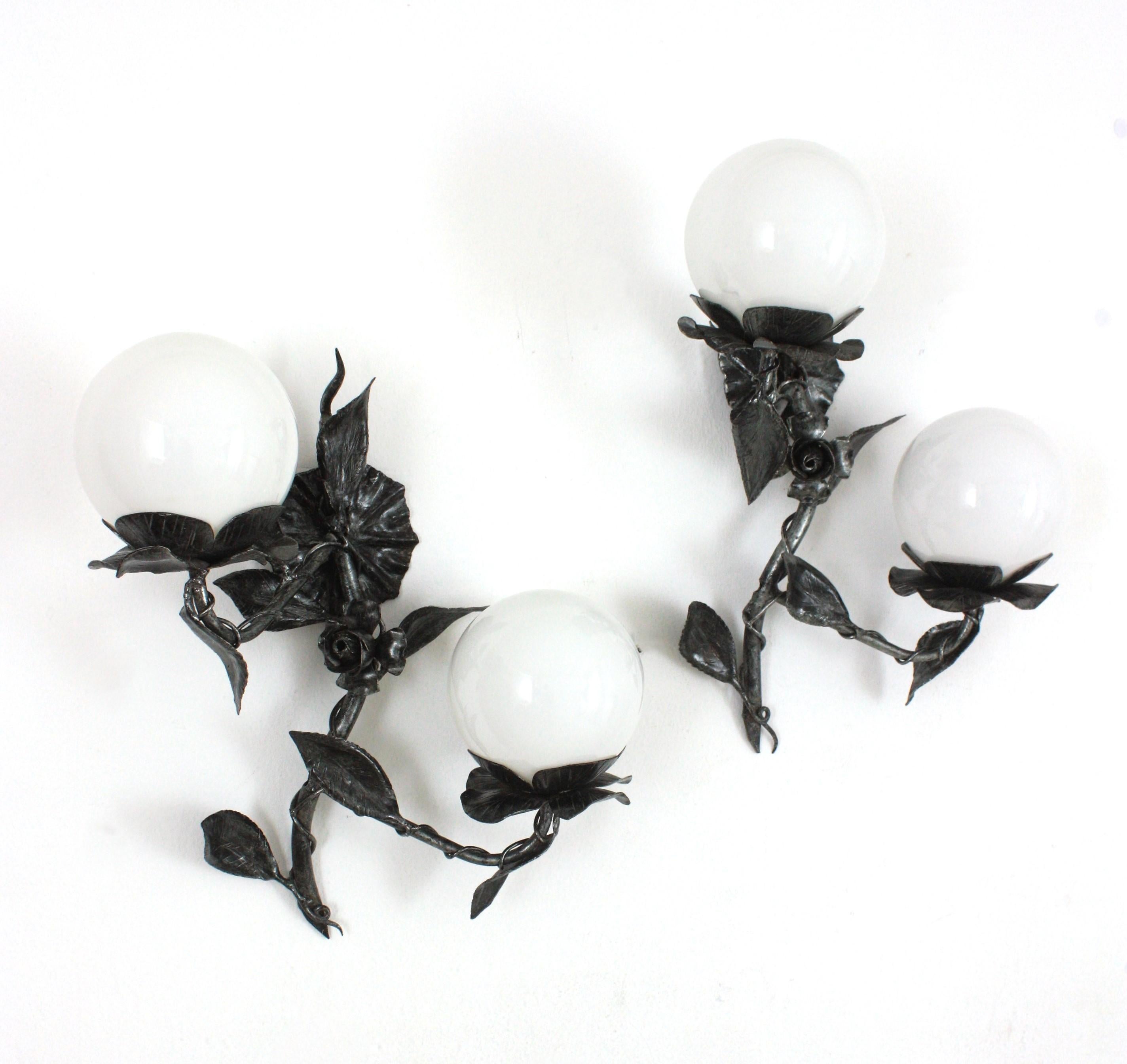 Pair of Foliage Floral Two Light Wall Sconces in Wrought Iron with Milk Glass Globes
Two light wall sconces with opaline glass globe shades and naturalistic design, Spain, 1940s.
This pair of wall lights was entirely made by hand patinated iron.