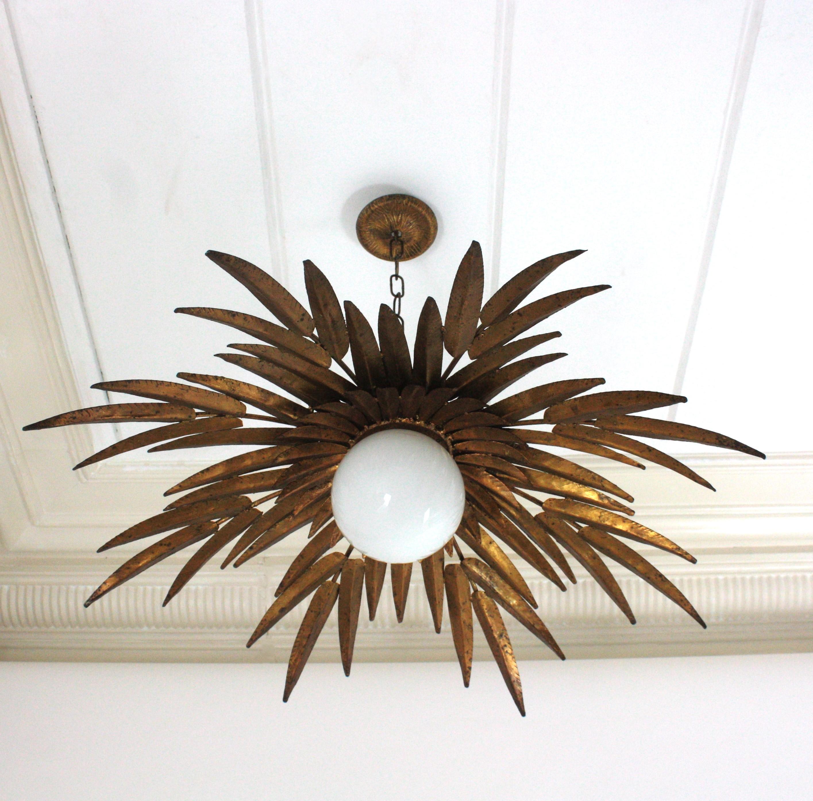 Large Spanish Sunburst Leaves Light Fixture in Gilt Iron with Milk Glass Globe

Outstanding Foliage Sunburst Flush Mount Ceiling Light with Milk Glass Globe by Ferro Art, Spain, 1950s
Large size.
To be used as ceiling light fixture or as chandelier