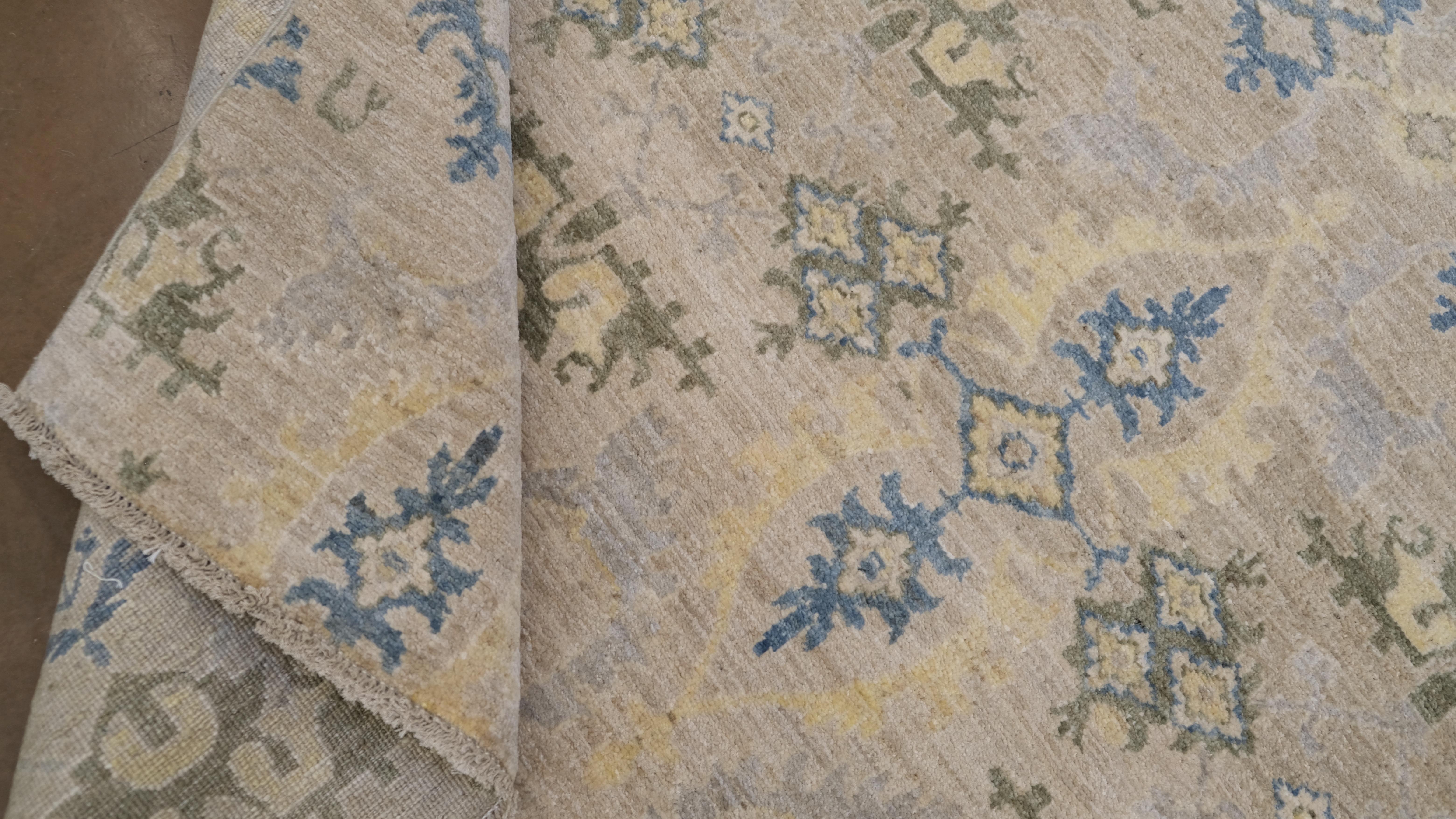 Dieser exquisite handgeknüpfte Wollteppich aus Pakistan verleiht Ihrem Raum zeitlose Eleganz. Dieser Teppich mit klassischem Blumenmuster kombiniert sanfte Pastelltöne in Blau, Grün und Beige und schafft so eine harmonische und heitere Ästhetik. Die
