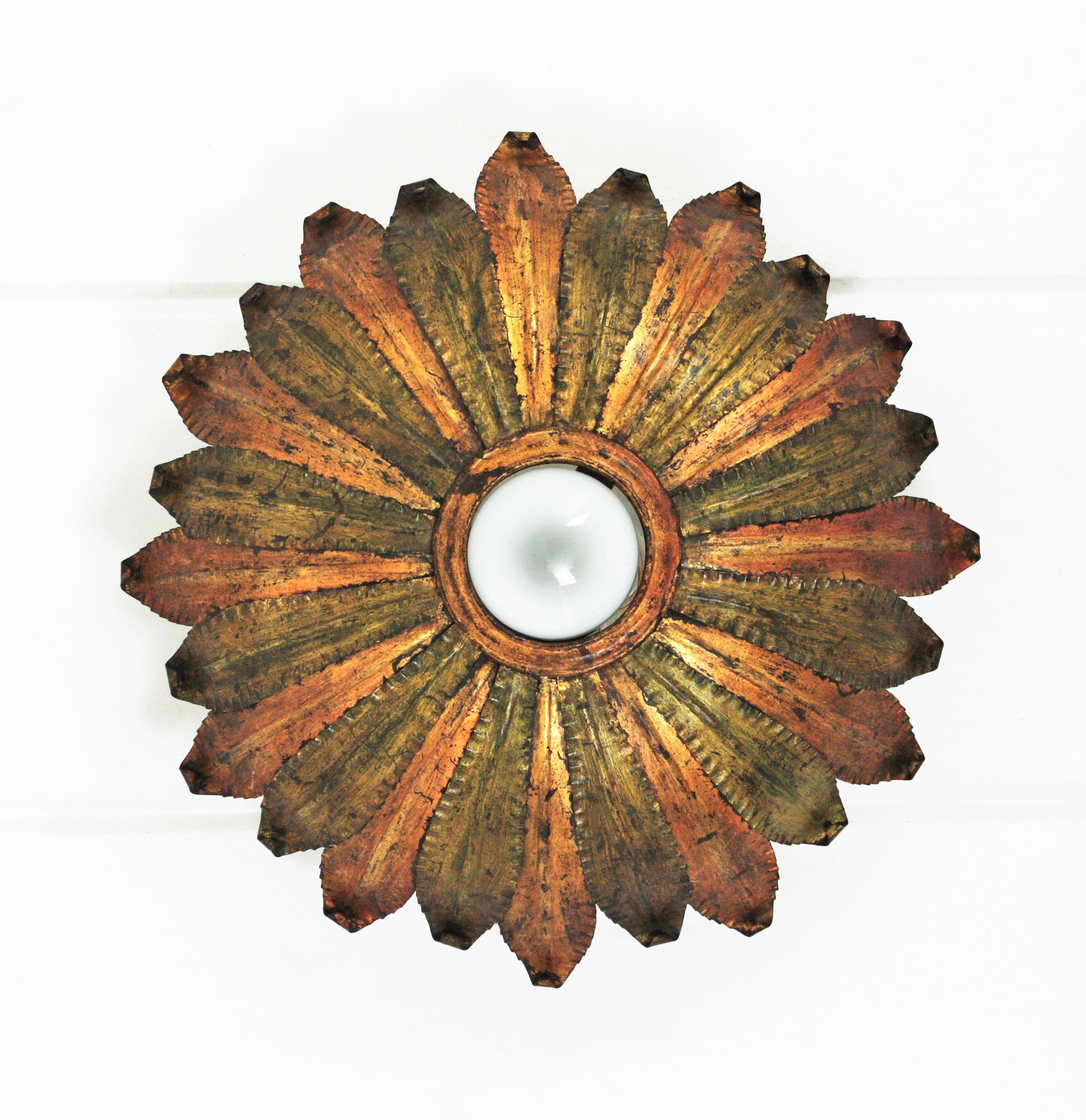 Sunburst light fixture, green and gilt iron, gold leaf, Spain, 1950s.
Eye-catching hand-hammered iron sunburst light fixture with a highly decorative original patina in gold leaf gilding and green color. 
This pieces a frame of alternating iron