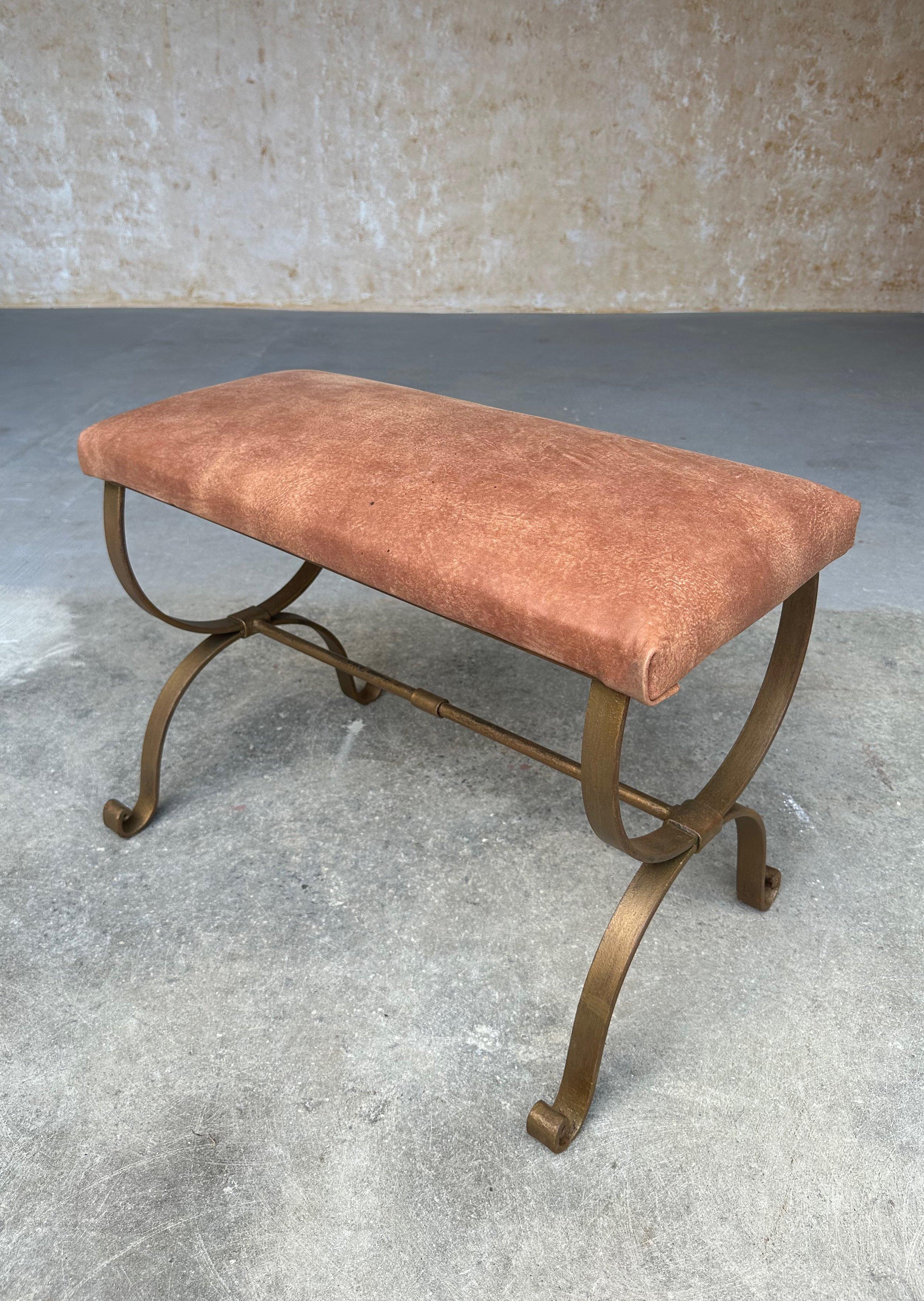 This elegant gilt iron bench was recently crafted by skilled artisans and features scrolled legs and a stretcher with a decorative center band. Handmade by expert European craftsmen, it has a hand forged iron base with a hand applied gold paint
