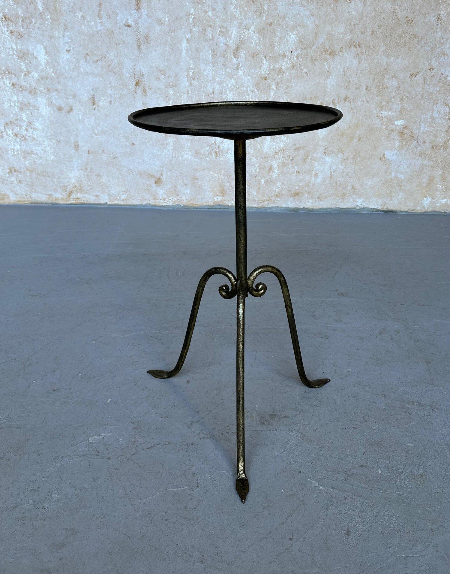 Une élégante table d'appoint de petite taille, récemment fabriquée par des artisans européens utilisant des techniques traditionnelles. Avec sa finition dorée appliquée à la main et ses subtiles nuances sombres, il repose sur une base tripode