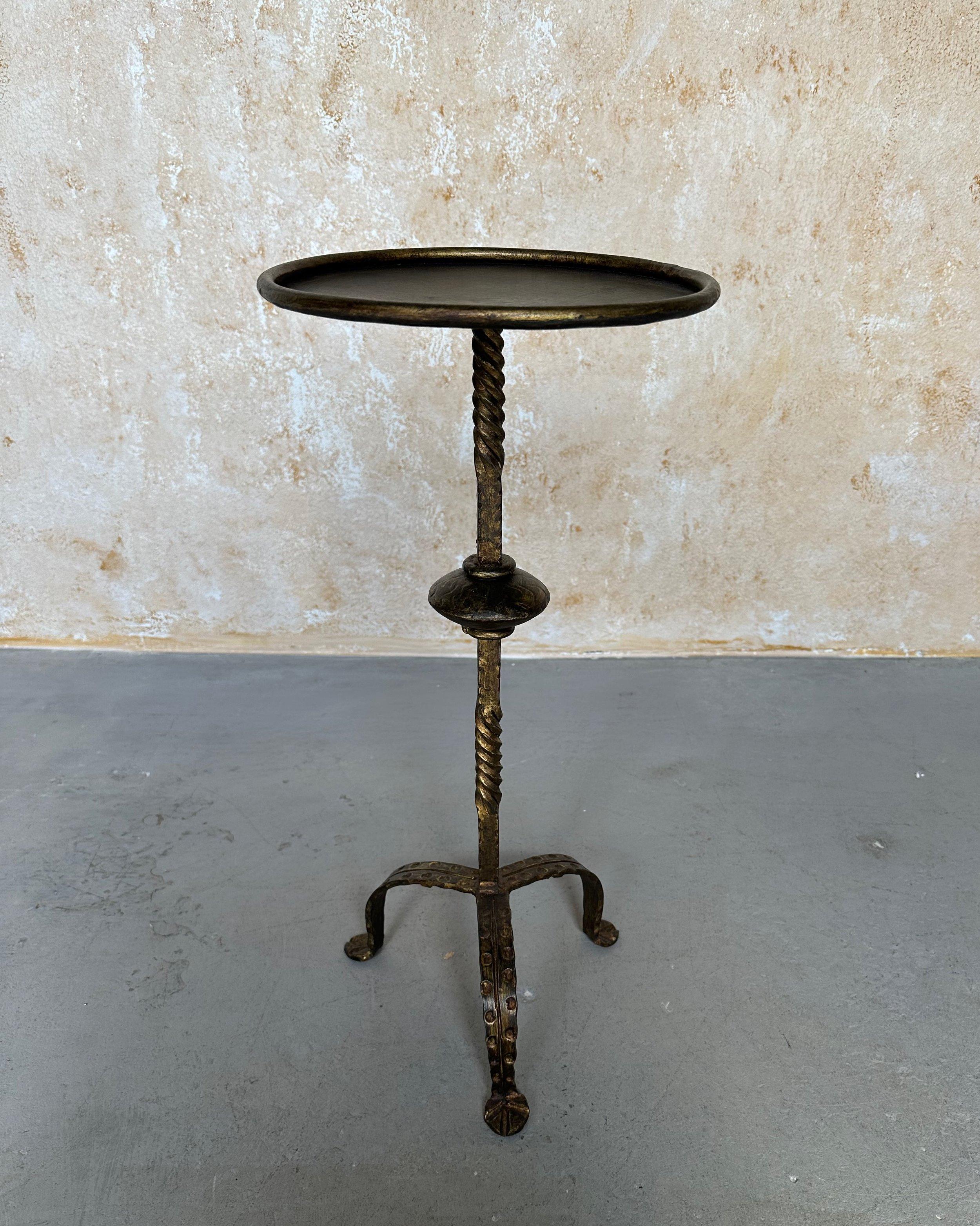 This unique and highly decorative small end table was recently hand crafted by skilled European artisans using traditional iron-working methods. It features a twisted stem with a central decorative element mounted on an elevated hammered tripod