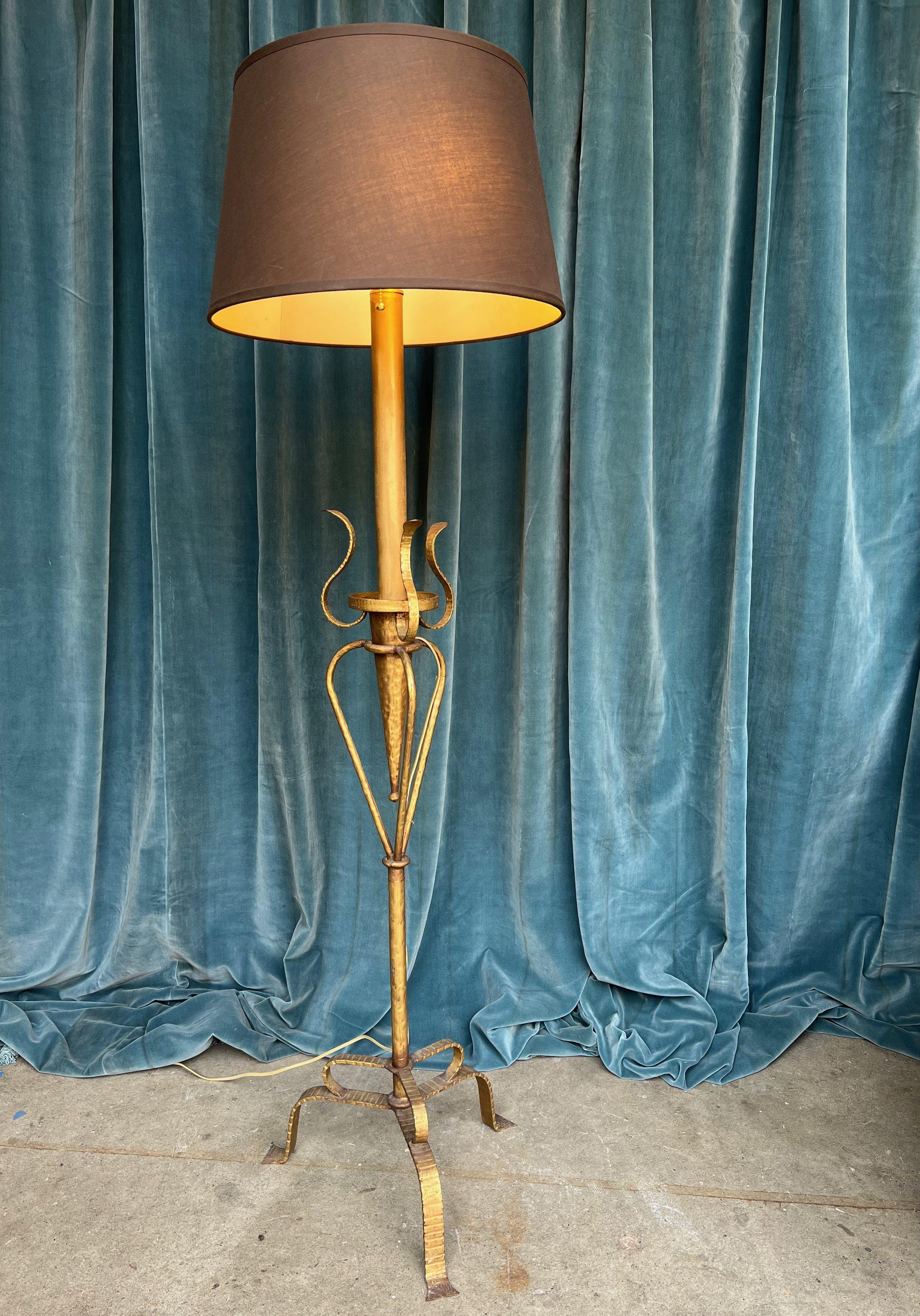 Introducing a unique Spanish gilt metal floor lamp from the 1950s. This captivating piece seamlessly blends Art Nouveau and mid-century modern styles. Its organic carved metal decorations and fluid design make it truly one-of-a-kind. Supported by a
