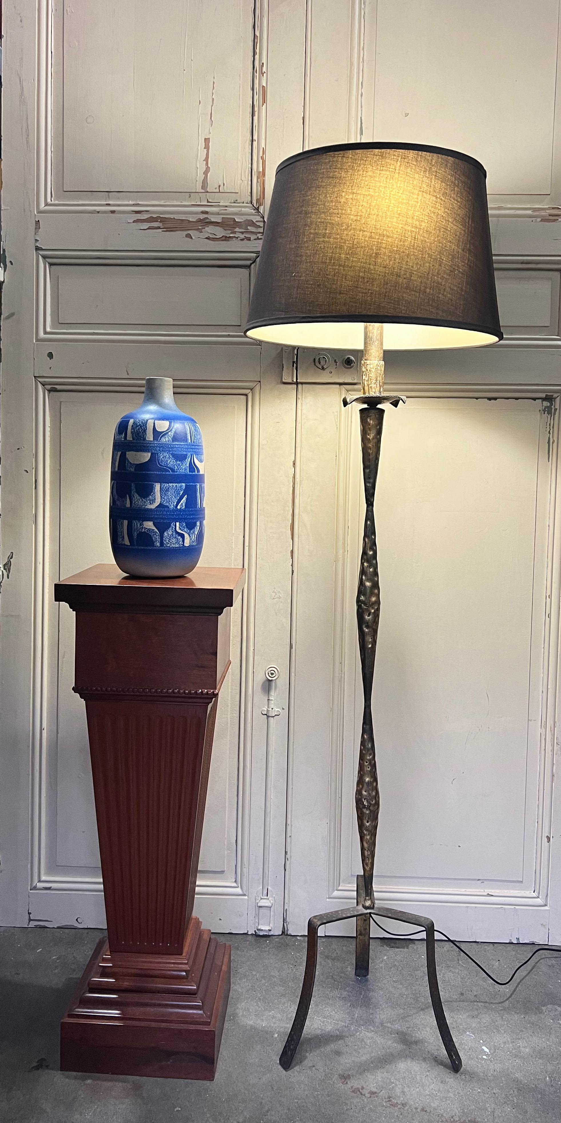 This Spanish Gilt Iron Floor Lamp, hailing from the mid-century modern era of the 1950s, stands tall on an elongated tripod base. The gilt iron and metal construction, with its rough hammered texture, brings an unusual and unique aesthetic to the