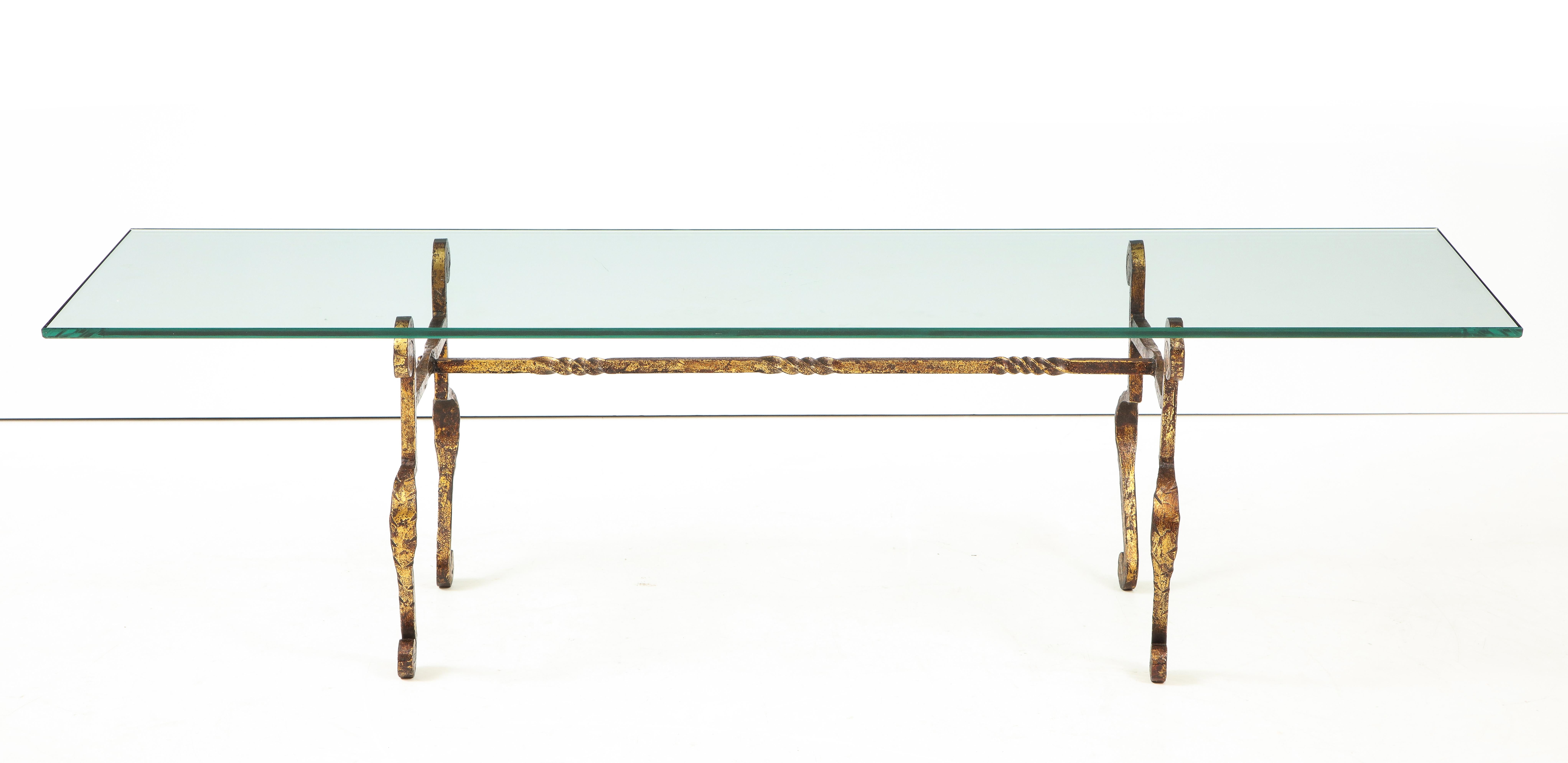 A hammered gilt metal coffee table with shaped legs and stretcher supporting a rectangular glass top,
Spain, circa 1960.
Size: 16 1/4