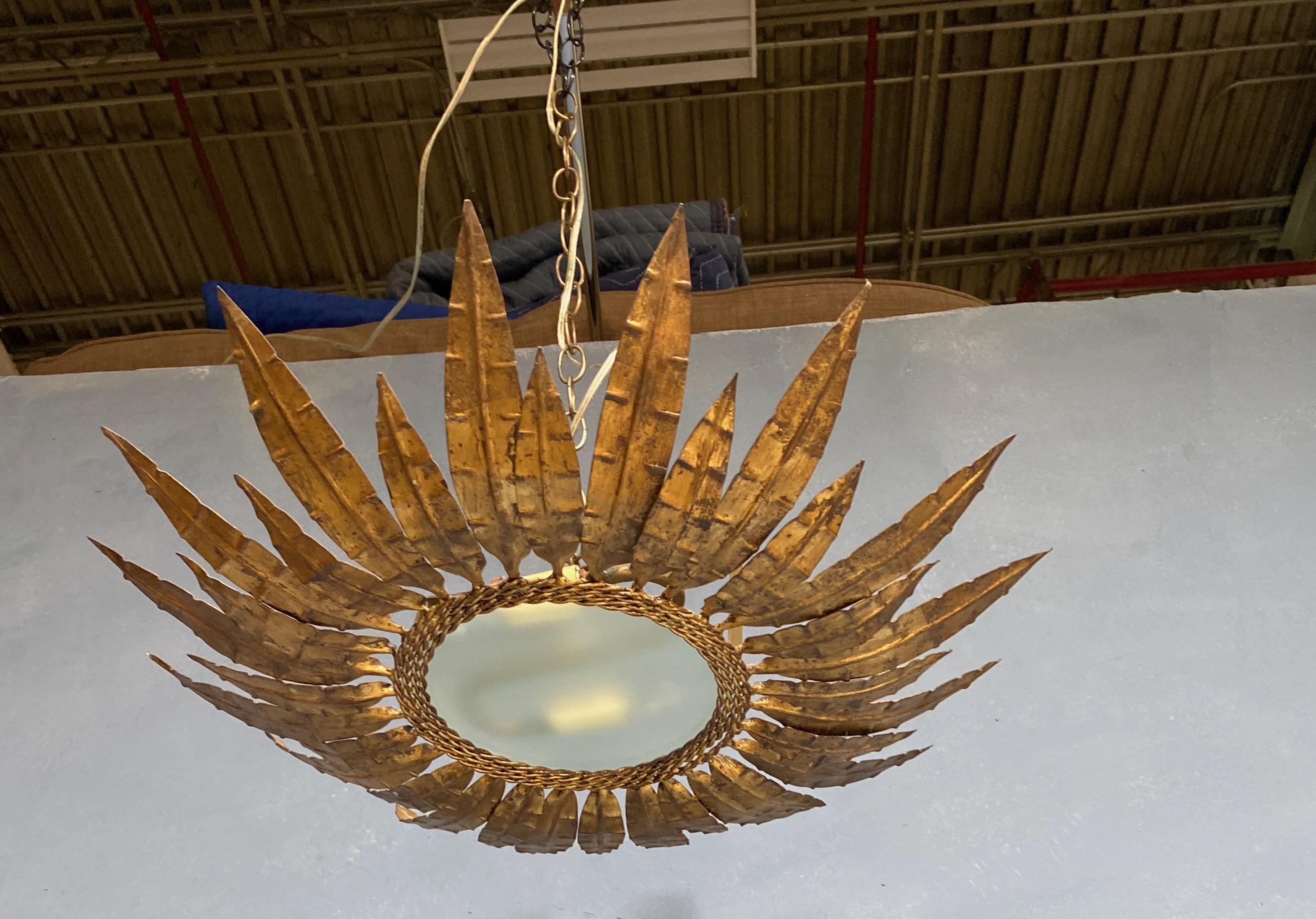 This magnificent flush mount ceiling fixture is a product of the 1950s Spanish design aesthetic. It features two alternating layers of leaf or feather motifs, all connected by four strands of twisted braids. The hand-applied finish presents a rich