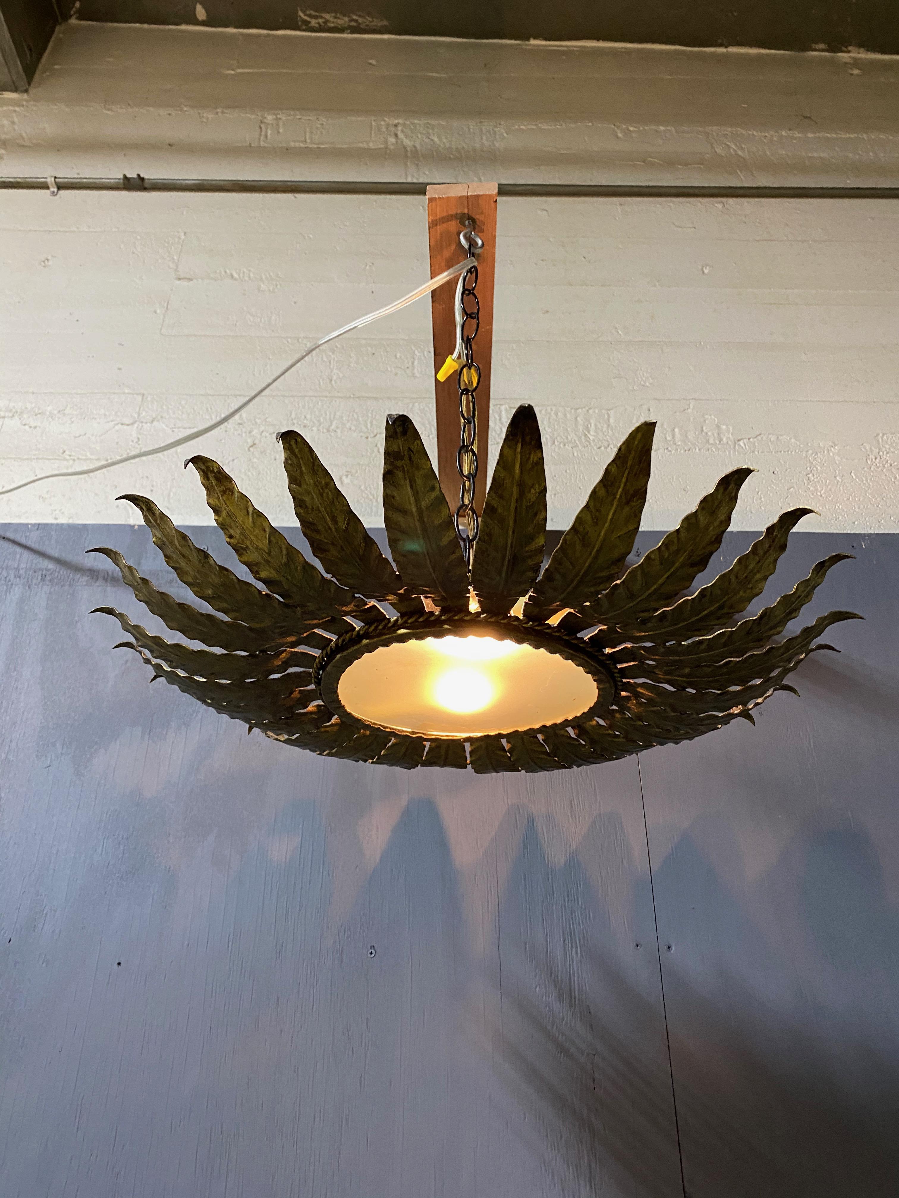 A large flush mount ceiling fixture with radiating leaf or feather motifs joined together with a twisted rope detail. The hand applied finish has a rich gold patina over a darker under coat. This fixture has been recently wired to accommodate two