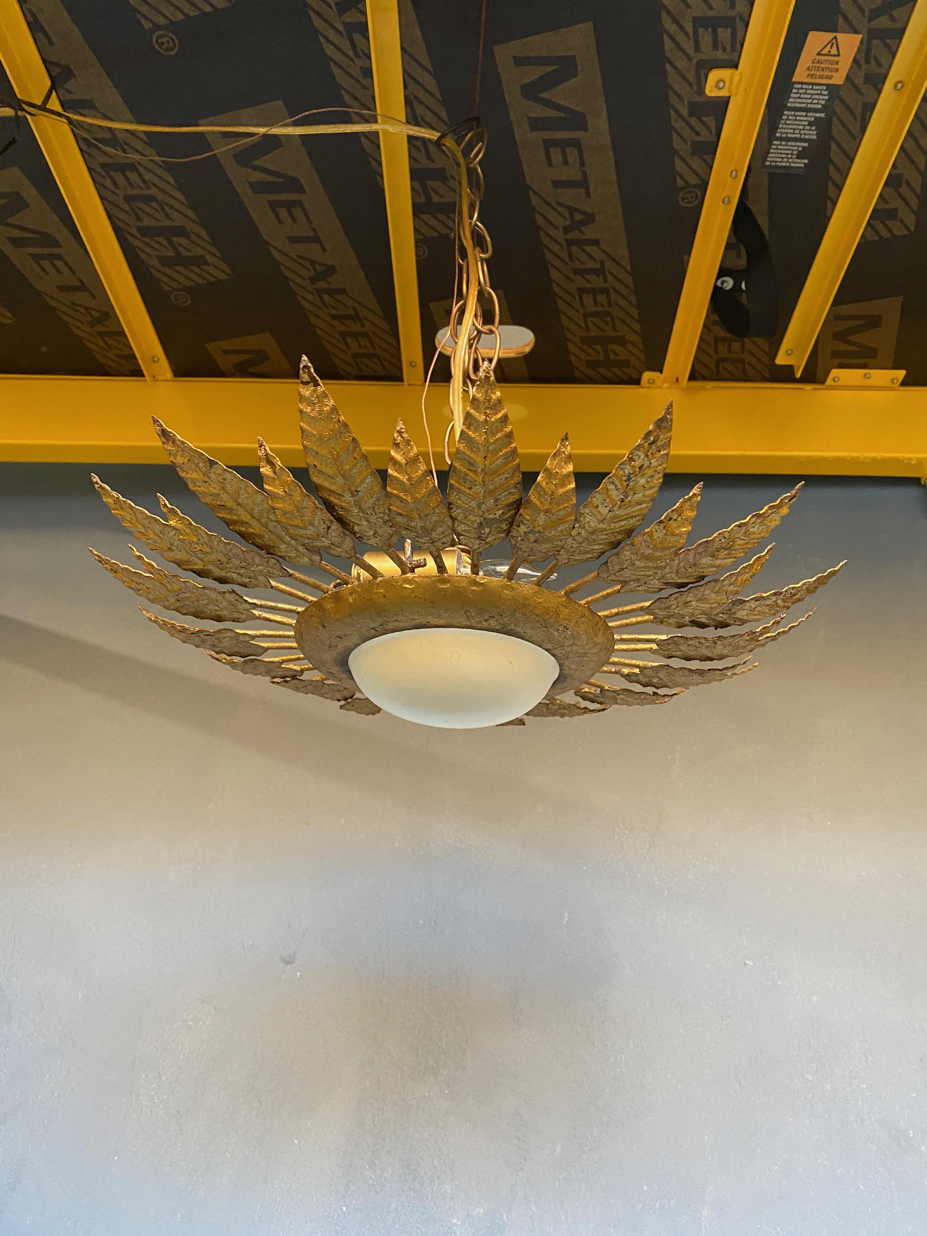Ce brillant plafonnier encastré en métal doré datant des années 1960 est un véritable chef-d'œuvre de l'artisanat espagnol. Son cadre solide renferme un globe blanc convexe en opaline, et il est orné d'une double rangée de feuilles longues et