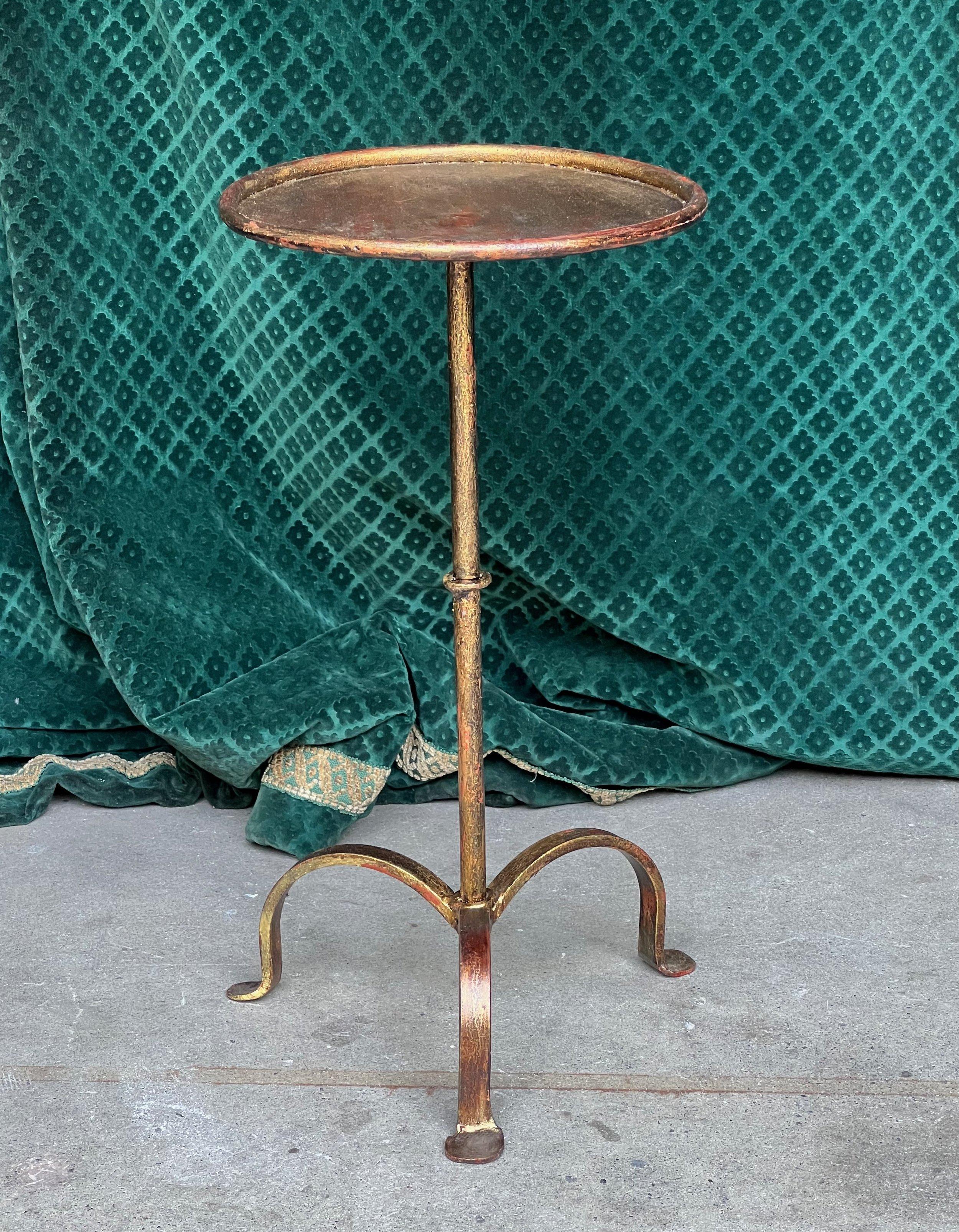 An enchanting small gilt iron martini table from Spain, a remarkable fusion of aesthetics and utility, designed to elevate the ambiance of your living space. This sophisticated drinks table features a distinct tripod base with three gracefully