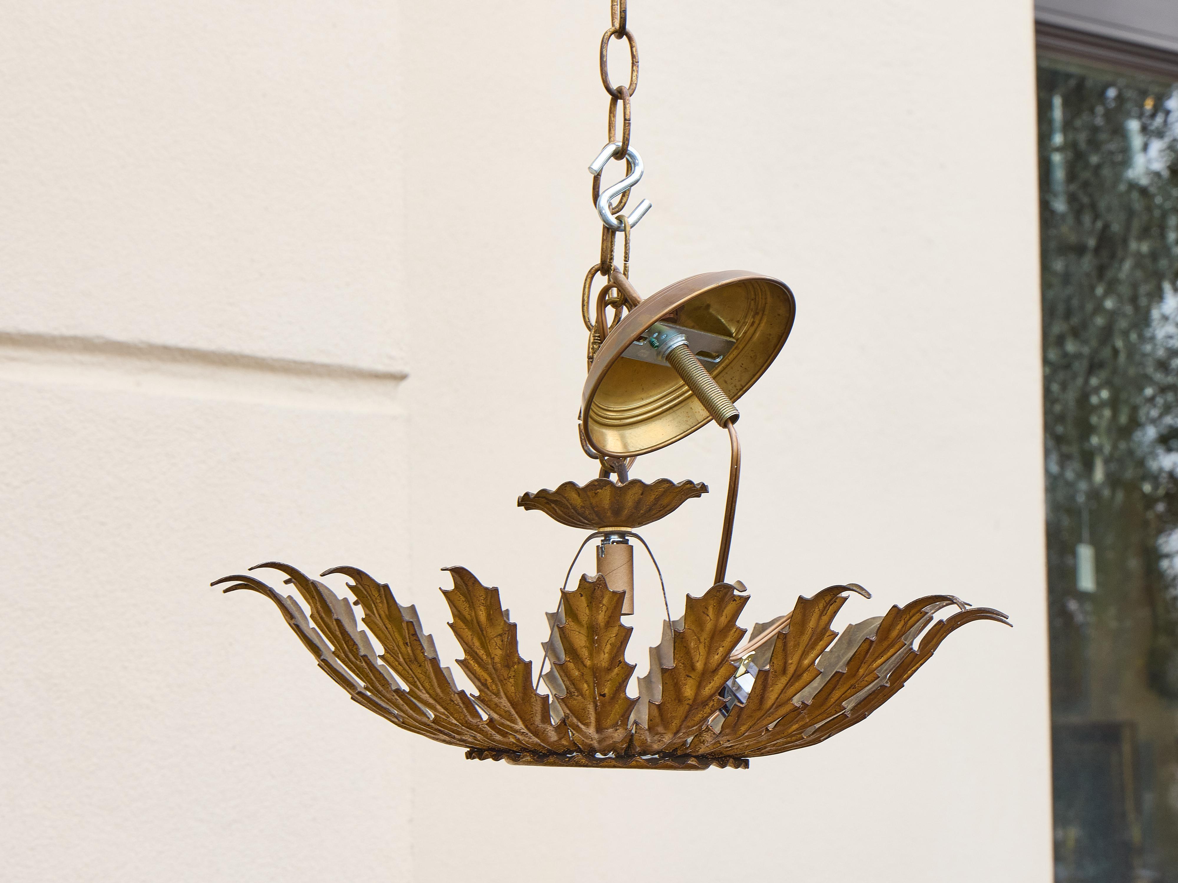 Ce luminaire espagnol en métal doré, datant des années 1950-1960, s'inspire des motifs classiques de feuillage et de l'artisanat du milieu du siècle dernier et rayonne d'un flair sculptural. La forme circulaire présente une succession de feuilles de