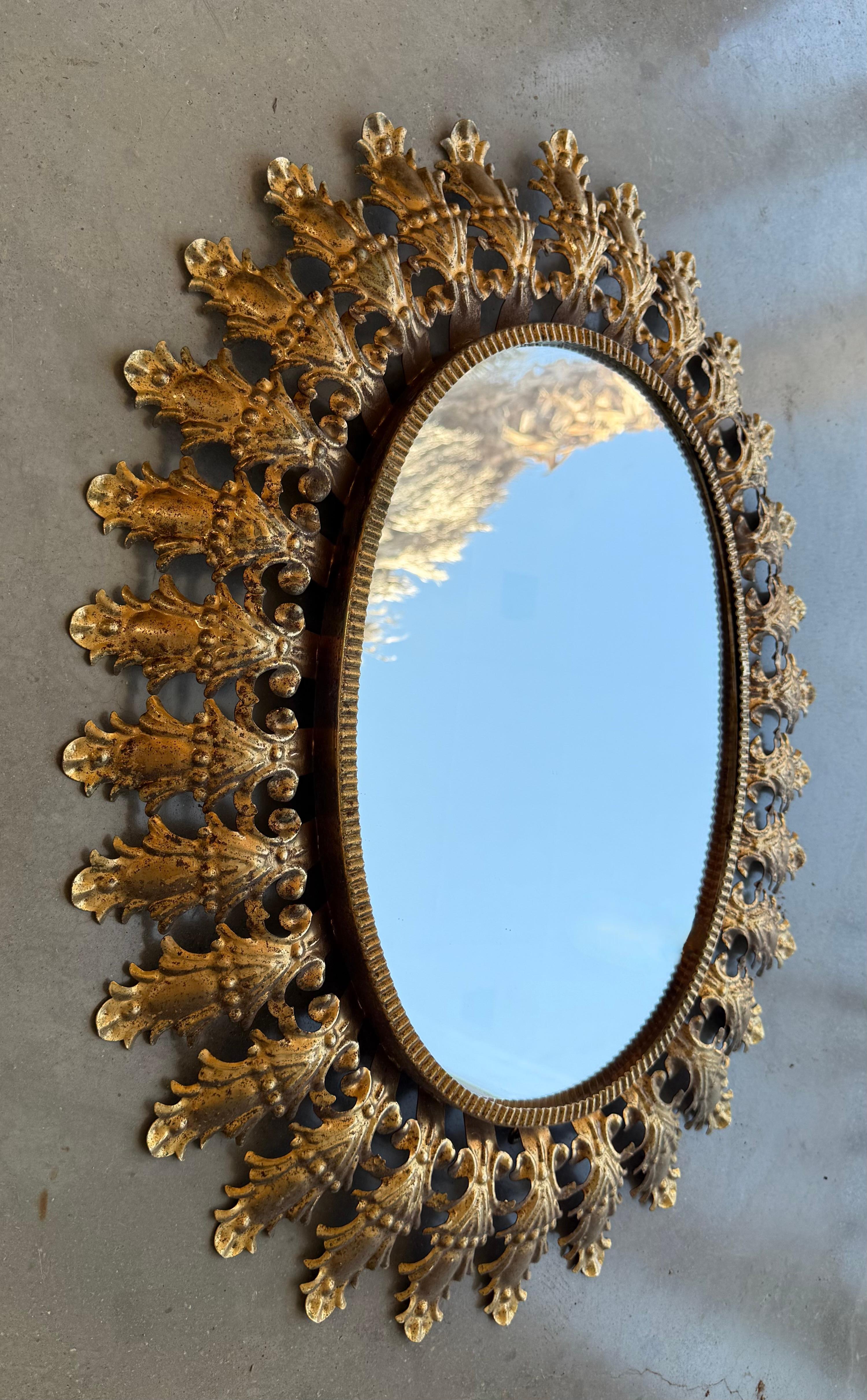 Miroir ovale en métal doré des années 1950 avec un cadre à motifs de feuilles.


