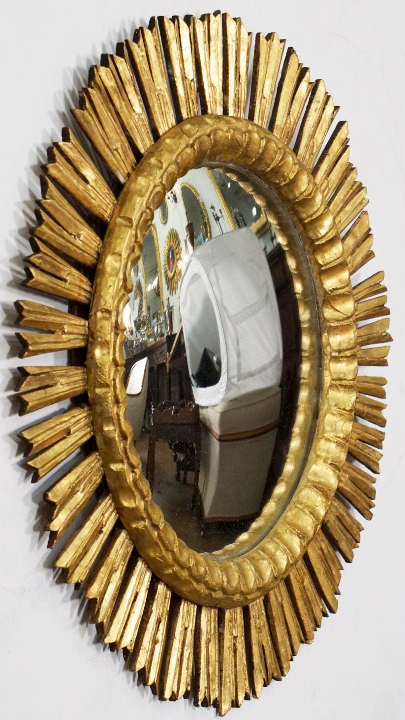 A lovely large Spanish gilt sunburst or starburst convex mirror, 25 inches diameter, with round mirrored convex glass center in a moulded frame surrounded by emanating gilded rays.