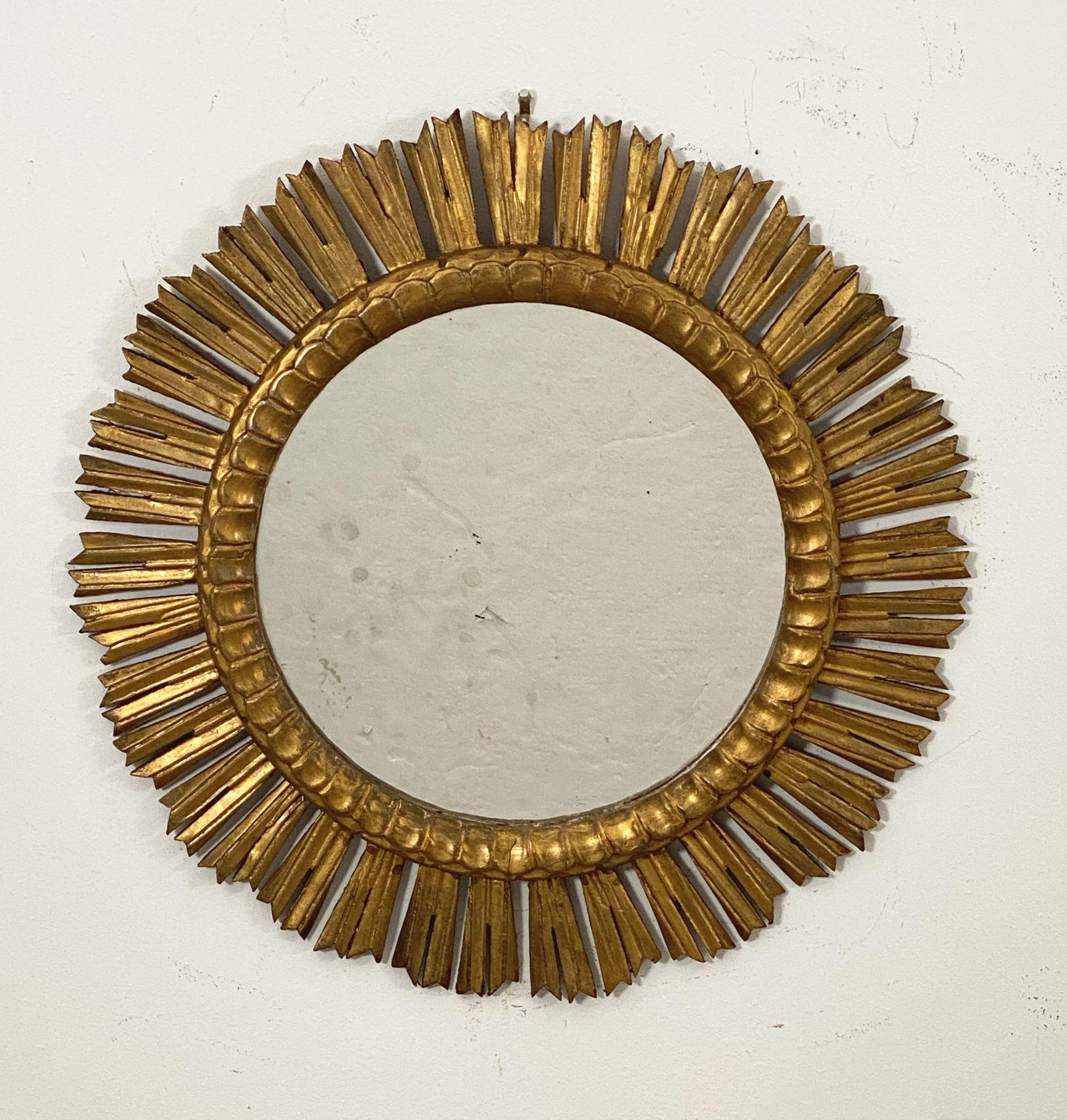 A beautiful Spanish gilt sunburst (or starburst) mirror with a row of finely gilded wooden rays arranged around a mirror plate glass center.

Dimensions: Diameter of 24 1/2 inches