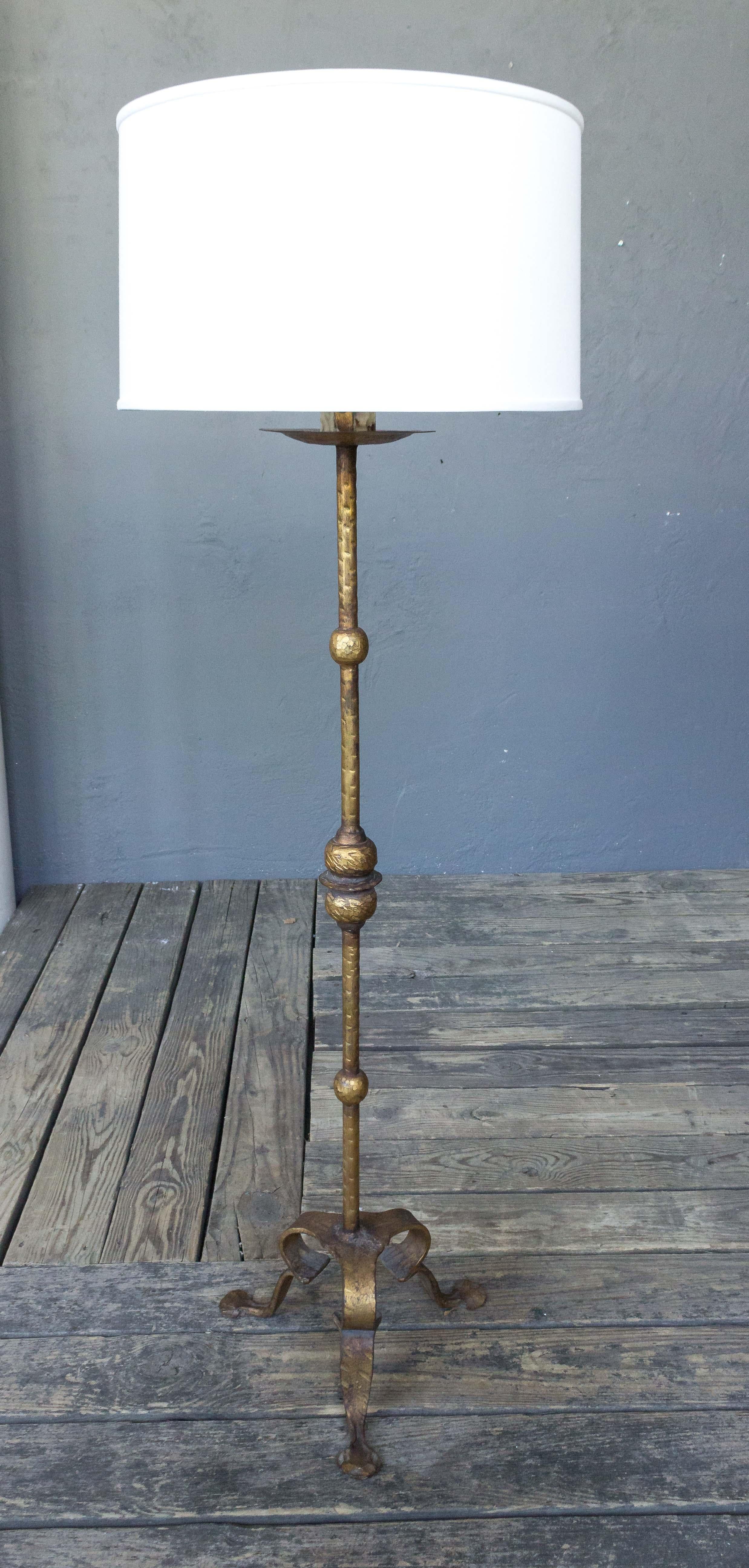 Presenting an extraordinary Spanish gilt wrought iron floor lamp of remarkable quality. This lamp, in very good vintage condition, stands at a height of 55 inches with an 18 inch diameter base. Please note that it has not been rewired, but a wiring
