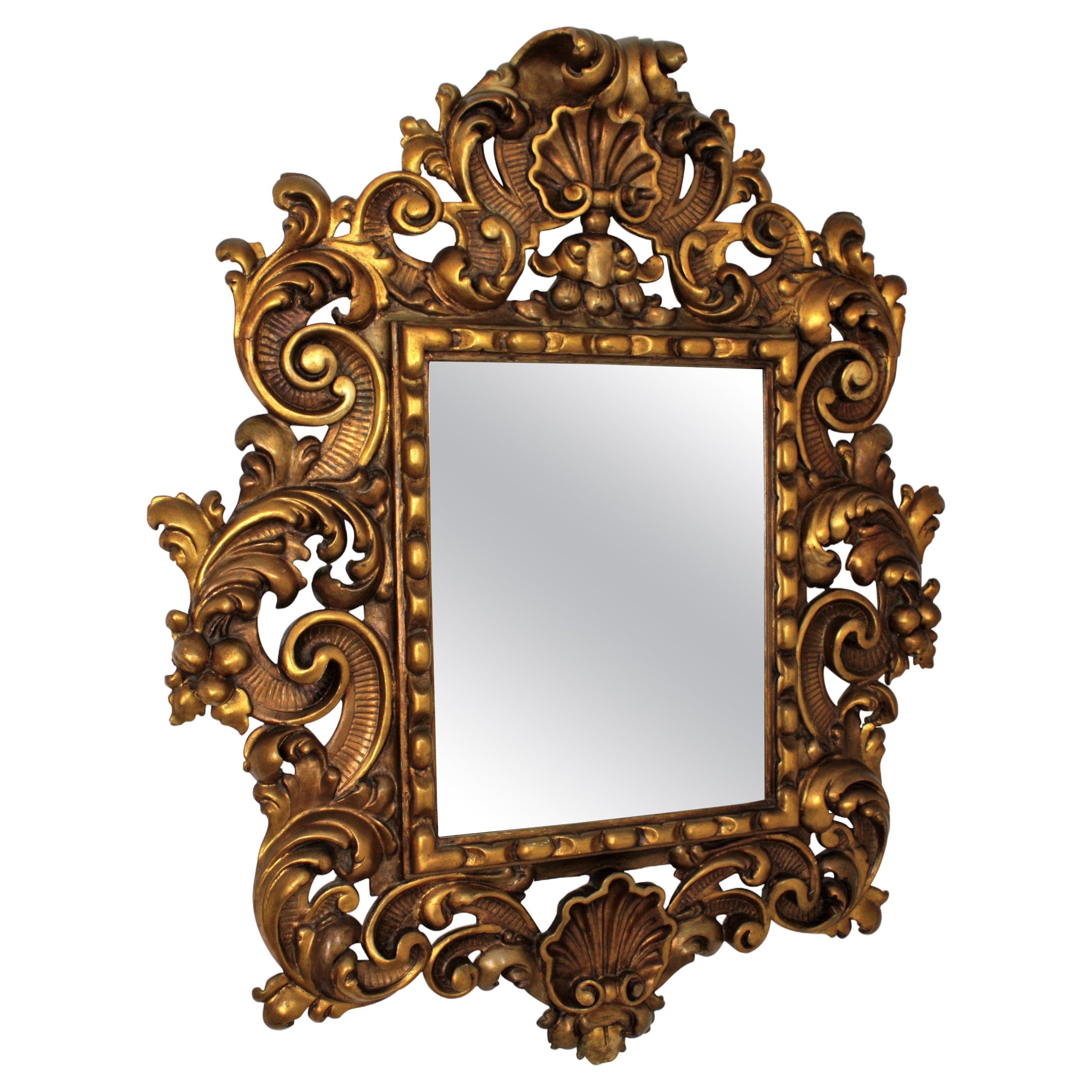 Spanish Rococo style mirror finely carved with beautiful naturalistic motifs. Spain, 1930s 
One of a kind spanish carved wall mirror
Gold leaf giltwood with an excellent aged patina. This exquisite frame has a richly decoration with scrolls, leaves,