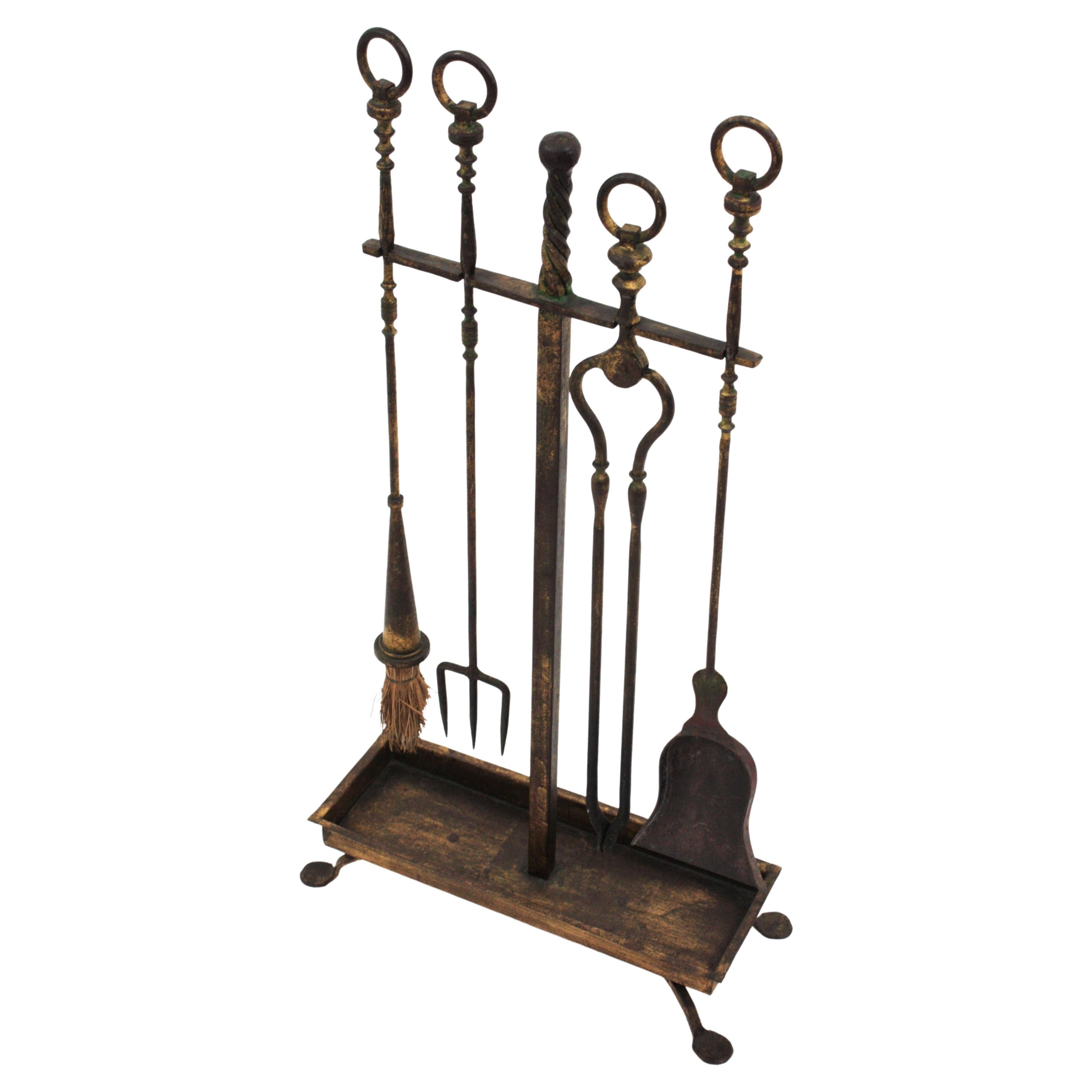 Beautiful Gothic style hand forged antique fireplace tool set on stand. Spain, 1930s.
The set includes four hand forged iron tools : a shovel, a log poker, broom, and tongs. The rack stands up on a four footed rectangular base with a cross shaped