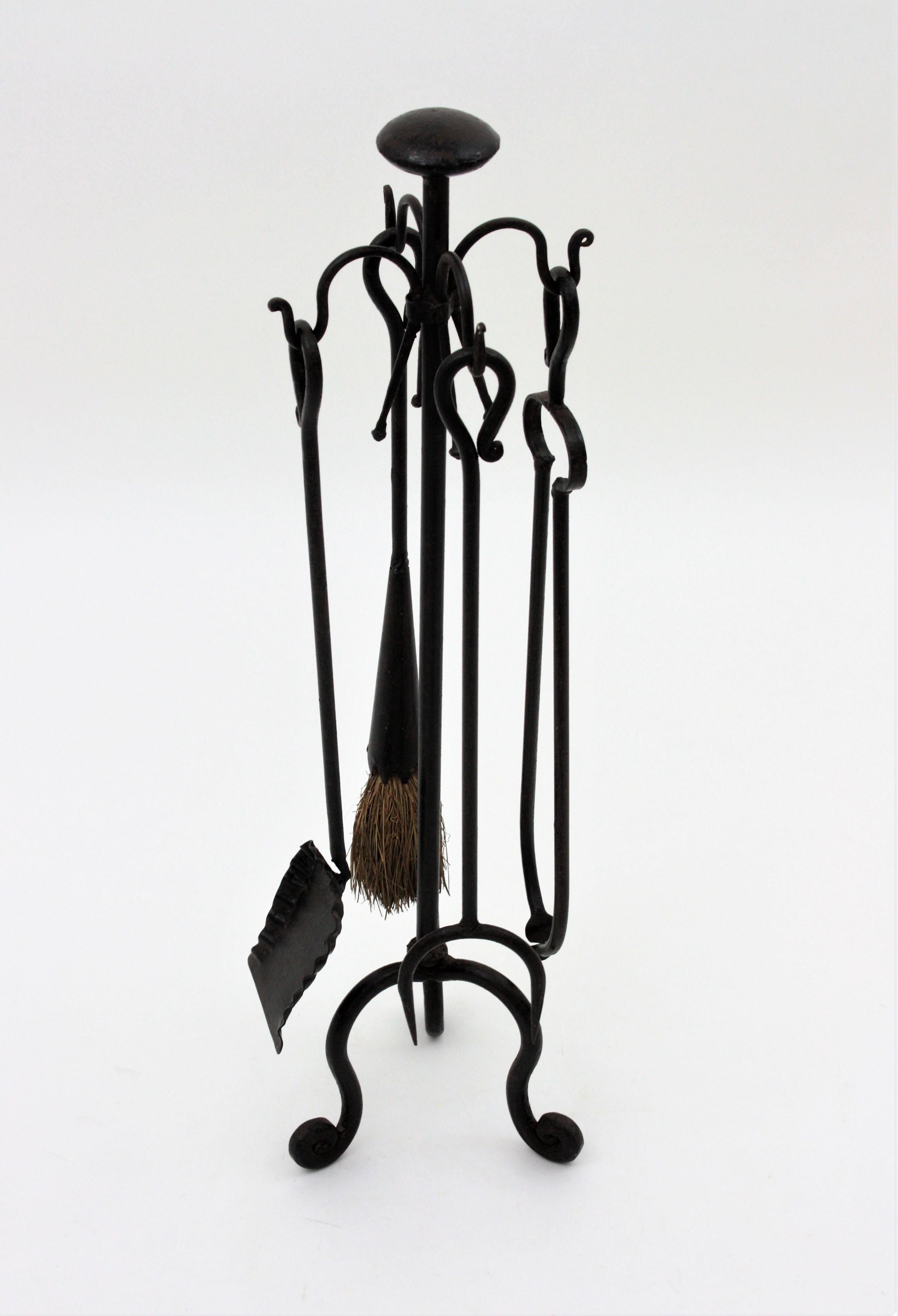 Beautiful Gothic style hand forged antique fireplace tool set on stand. Spain, 1940s
The set includes four hand forged iron tools : a shovel, a log poker, broom, and tongs. The rack stands up on a tripod base with scroll details, hook endings to