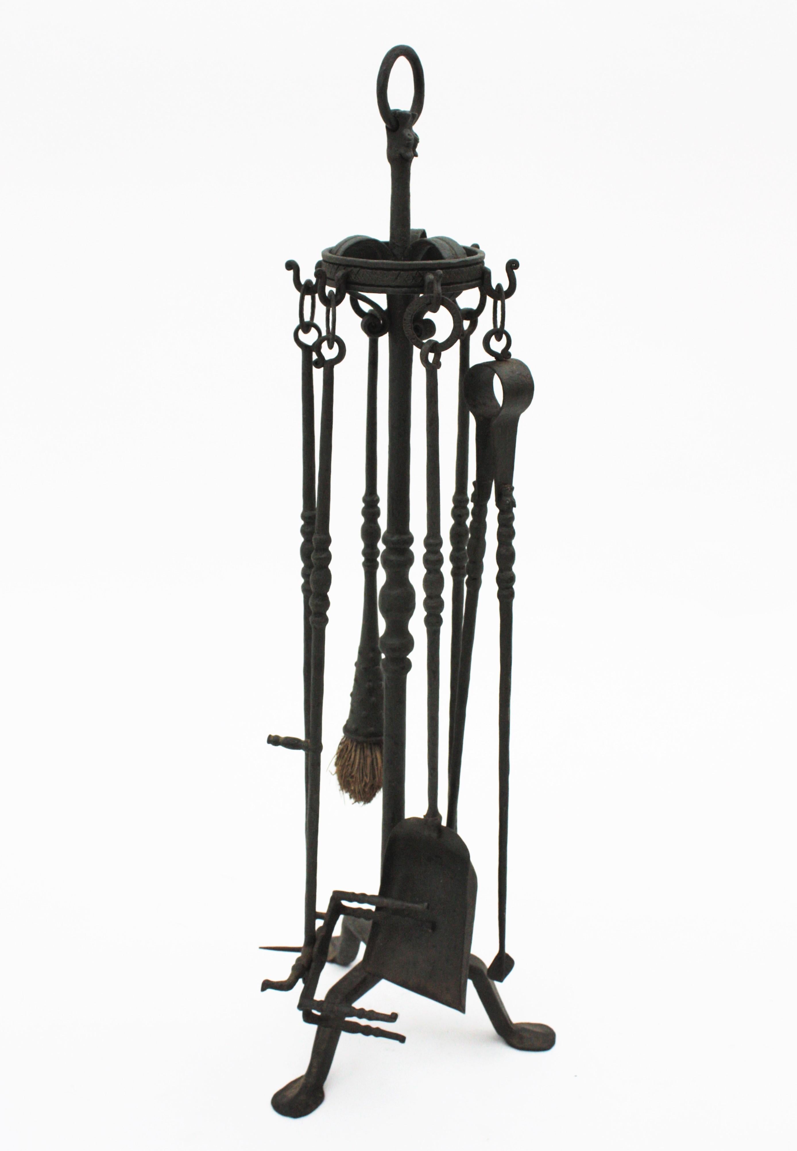 Spanish hand forged iron six-piece fireplace tool set Stand with scrolls ornamentation and dragon motif Spain, 1930s-1940s
This sculptural tools set stands up on a tripod base and holds six tools from iron rings. The tools have balls details nd