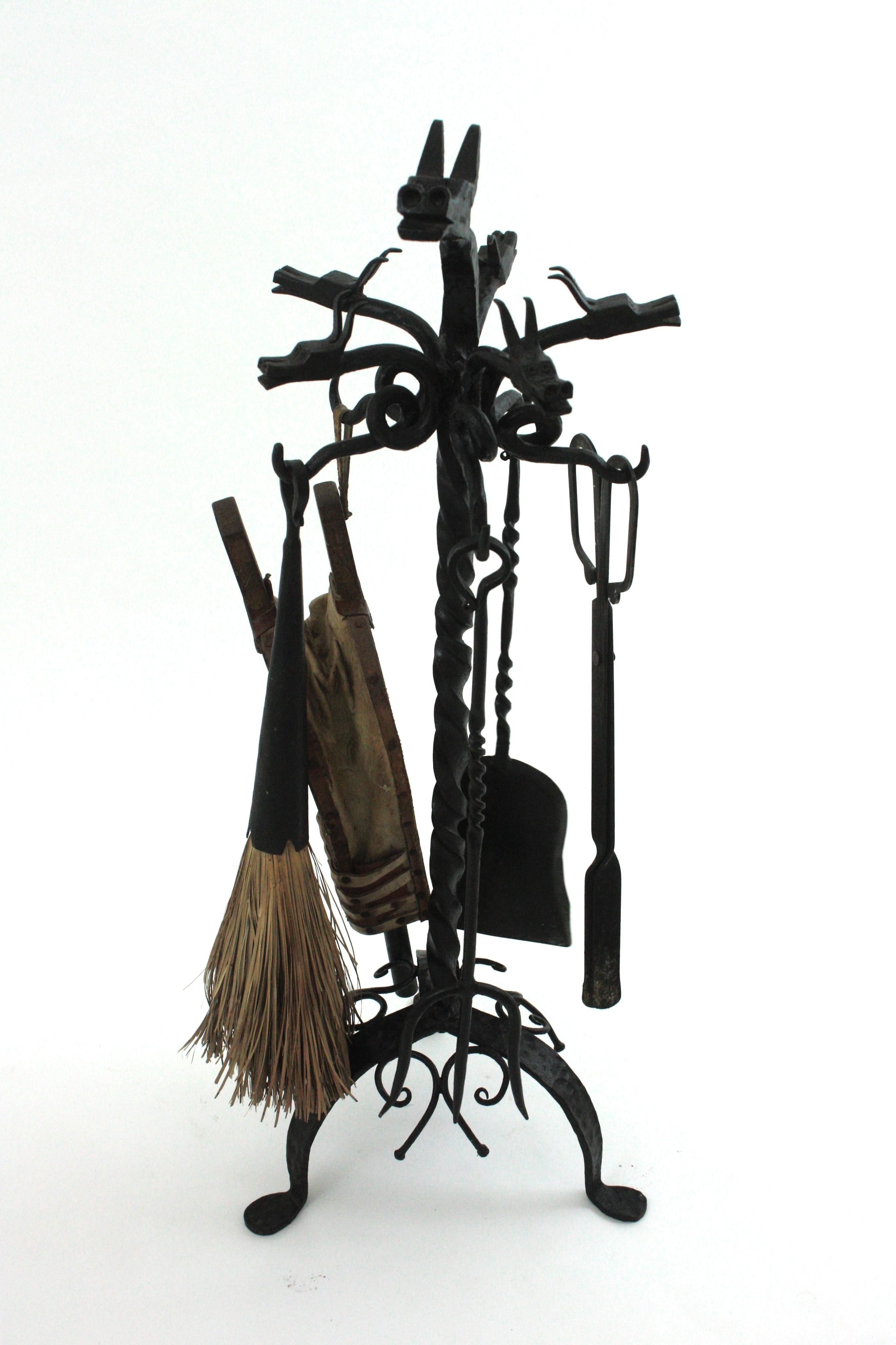Soporte de hierro forjado a mano español de cinco piezas para herramientas de chimenea con ornamentación de volutas y motivos de dragones, de hierro forjado. España, años 1920-1930.
Este conjunto escultórico de herramientas cuelga de una base