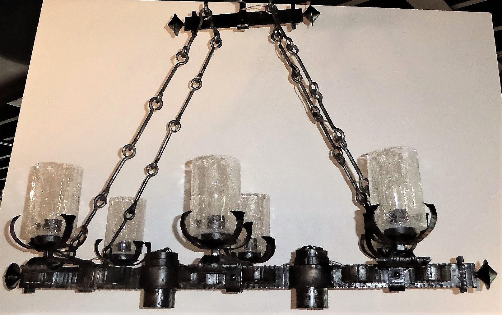 REDUCED FROM $1,550....From the 1960s, a Spanish Gothic style hammered and silvered iron 6 light chandelier. With a multiple C-curled design, the elongated hanging chandelier features 6 crackle glass globed lights and 2 down lights and four iron