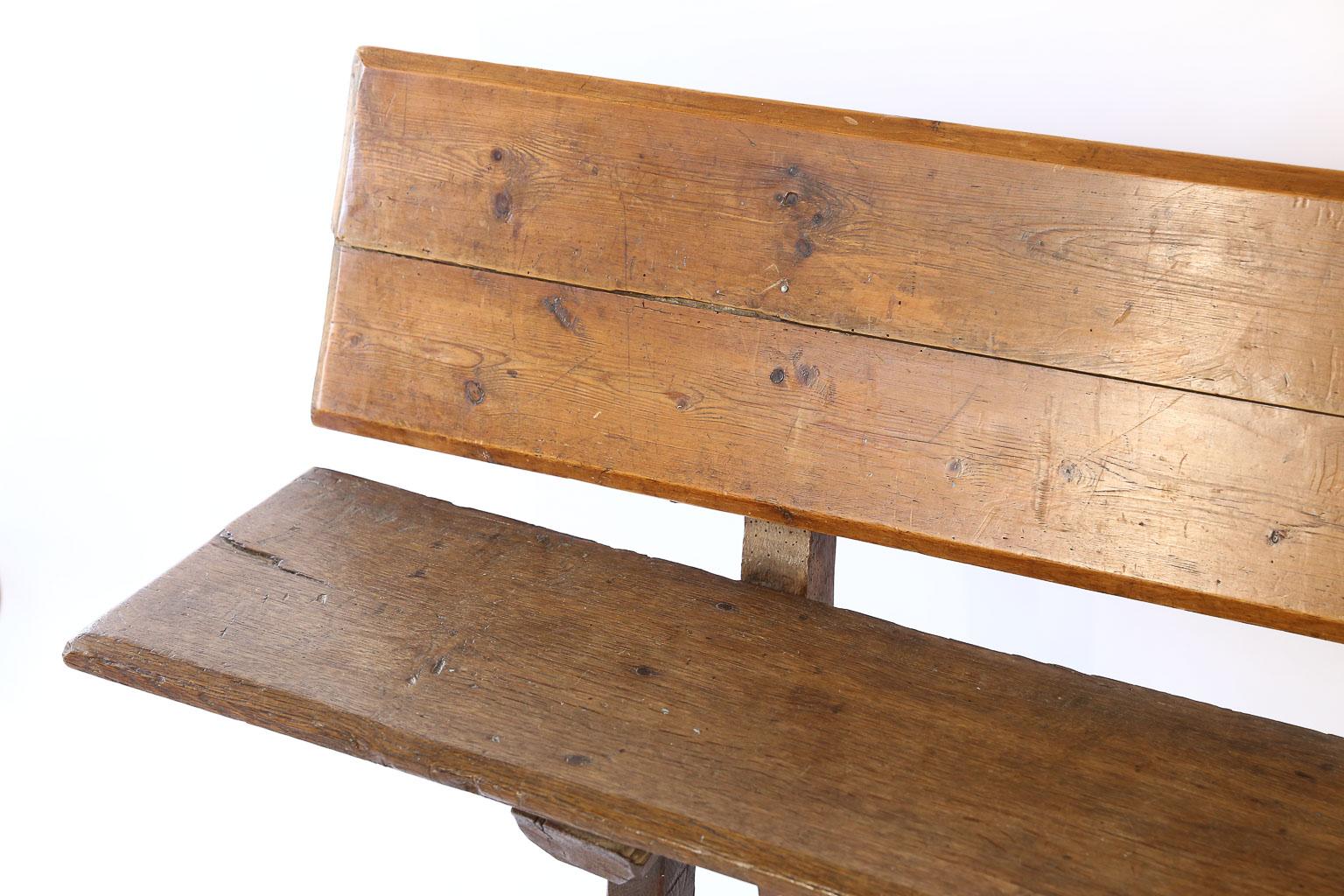 This is an antique Spanish hall bench with an iron trestle for support. The bench is made from mixed woods and has been waxed to a beautiful patina.