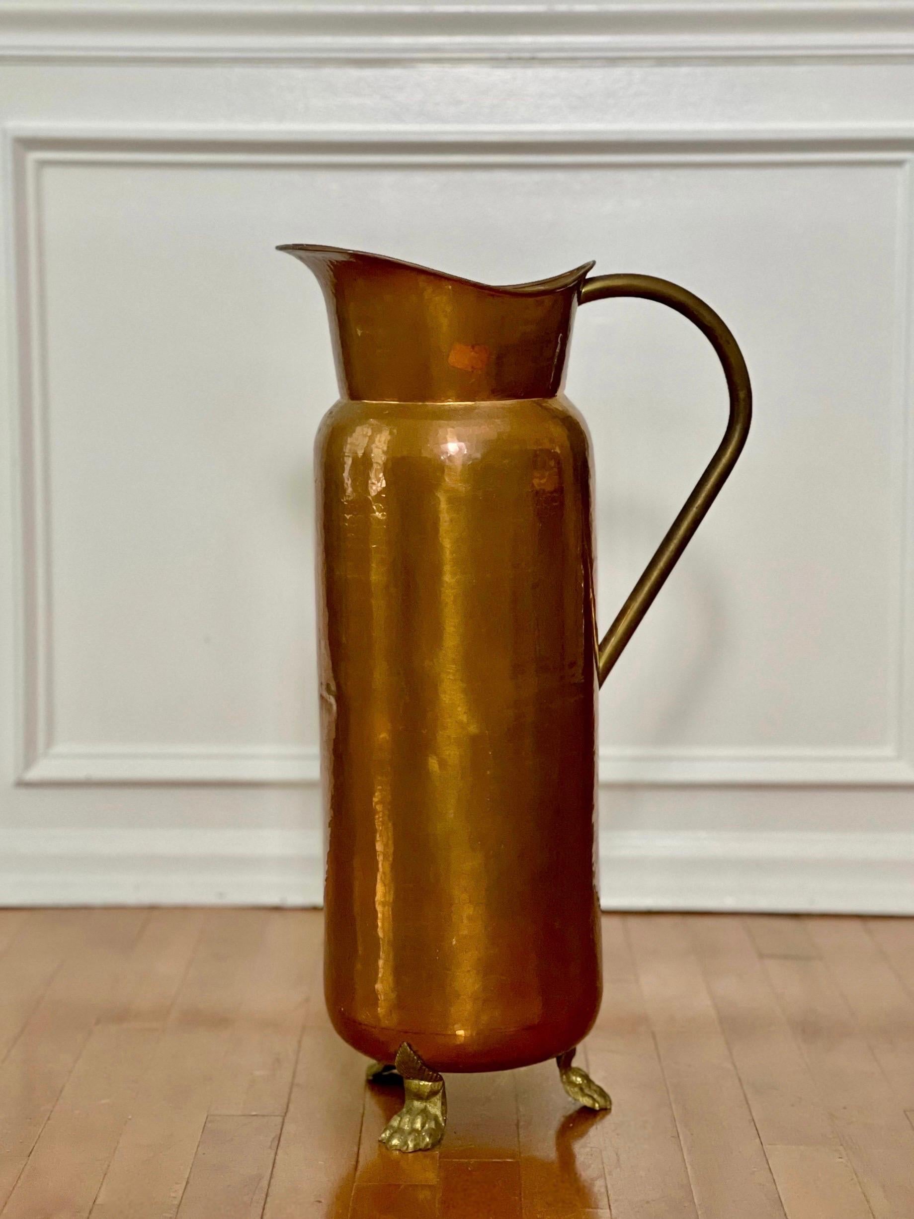 Portaombrelli a forma di brocca in rame e ottone in stile rustico con piedini ad artiglio, realizzato in Spagna all'inizio del 1900.  Ha un corpo alto dalla forma unica, con una grande maniglia in ottone e un ampio beccuccio e poggia su piedi a