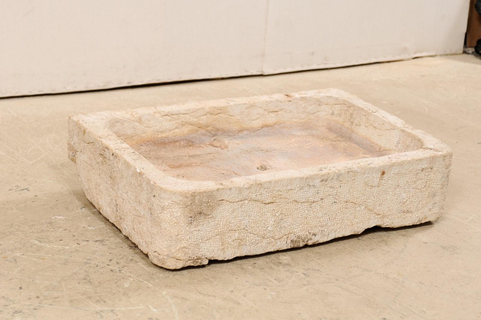 A Spanish sink with shallow basin from the 19th century, possibly older. This antique hand carved limestone sink from Spain has an overall rectangular-shape, which houses a shallow, rectangular basin within, with softly rounded corners. There is a