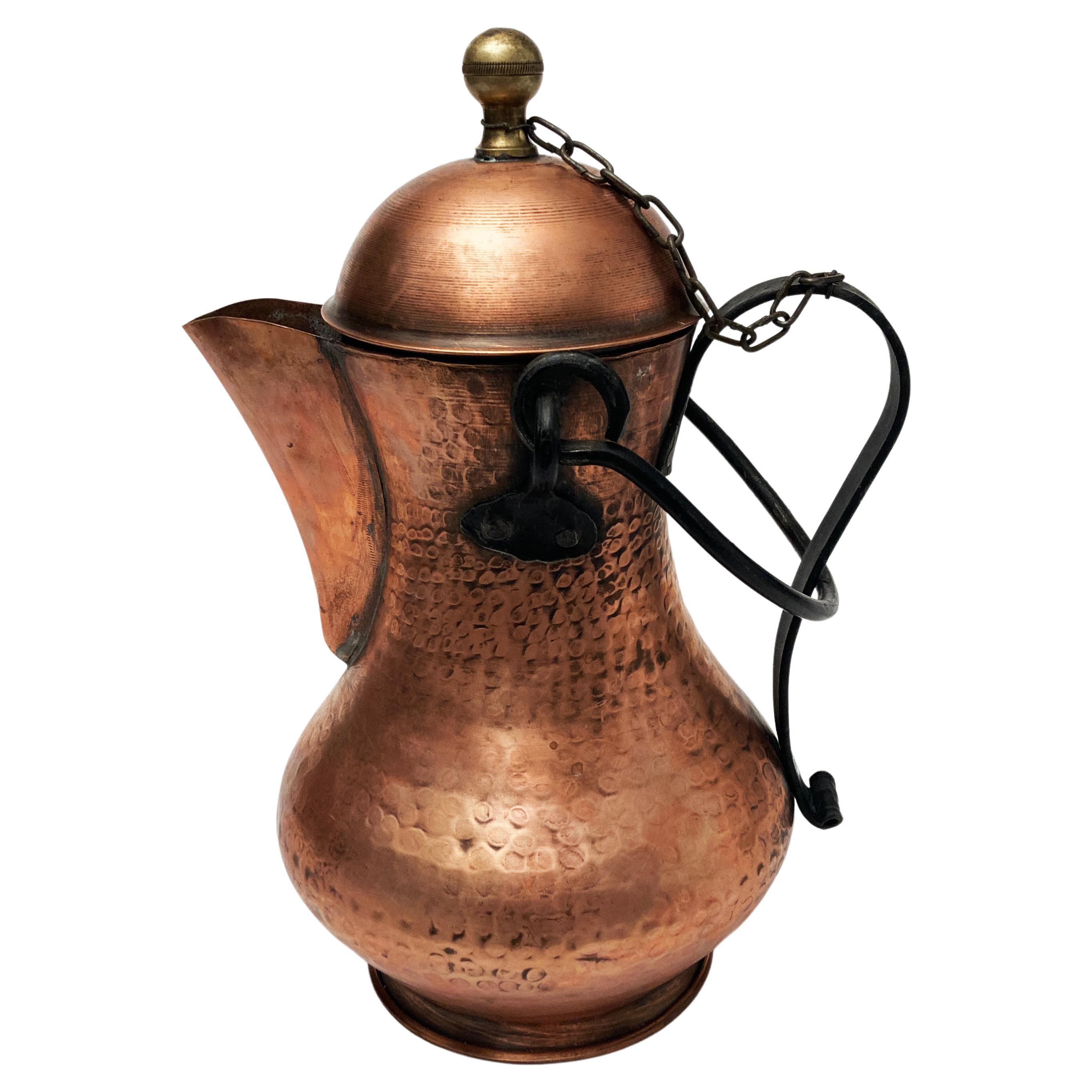 This beautifully crafted water vessel is most likely of Spanish creation during the early part of the 20th century. This hand-hammered pot has two wrought iron handles; one pouring handle and the other is a carrying handle. The lid is attached with