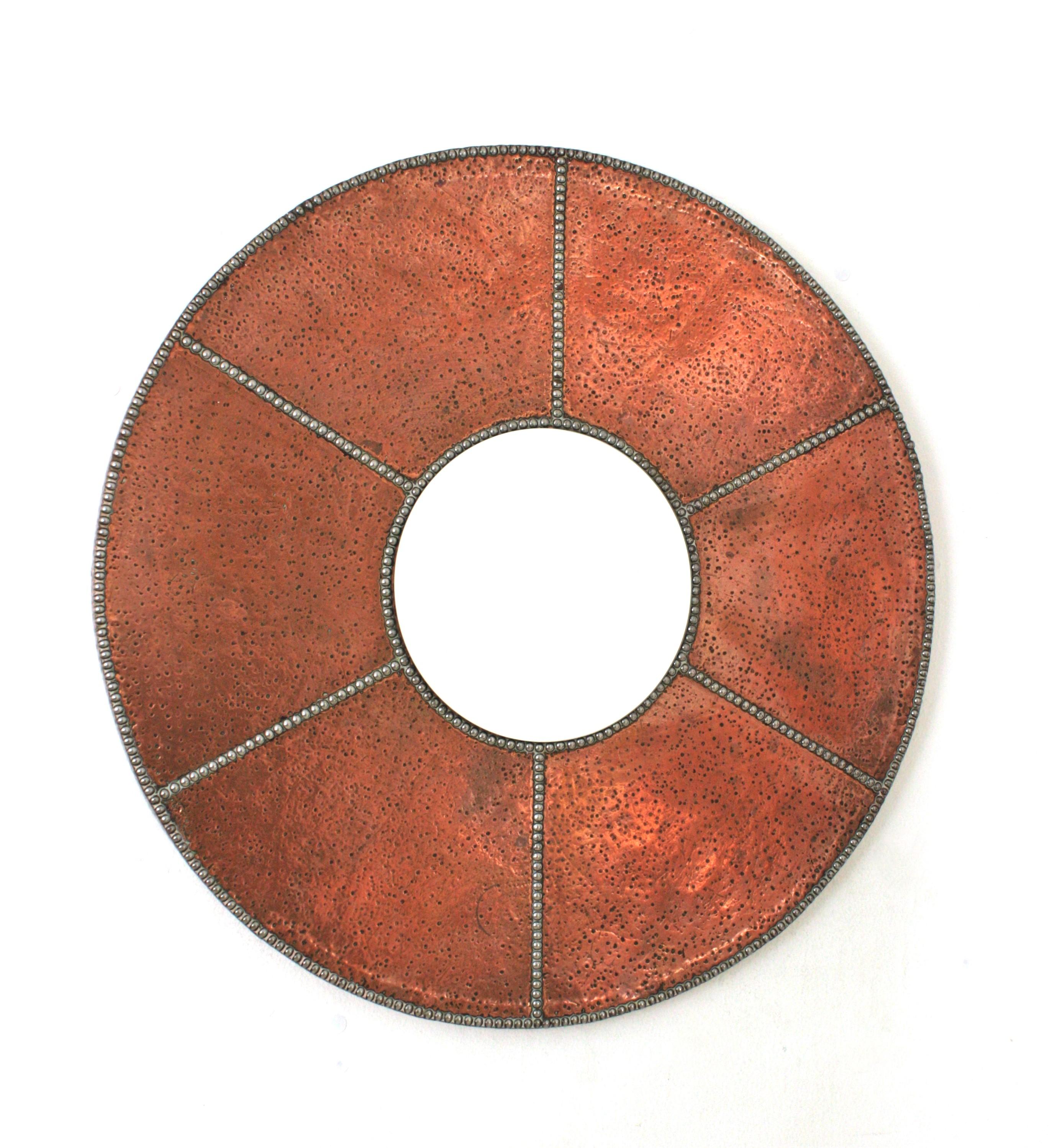 Miroir rond en cuivre martelé avec des clous en fer décorés de rayons de soleil, Espagne, années 1930-1940.
Ce miroir rond accrocheur est doté d'un cadre en cuivre entourant un verre central. Le cadre est fortement orné par les marques de marteau à