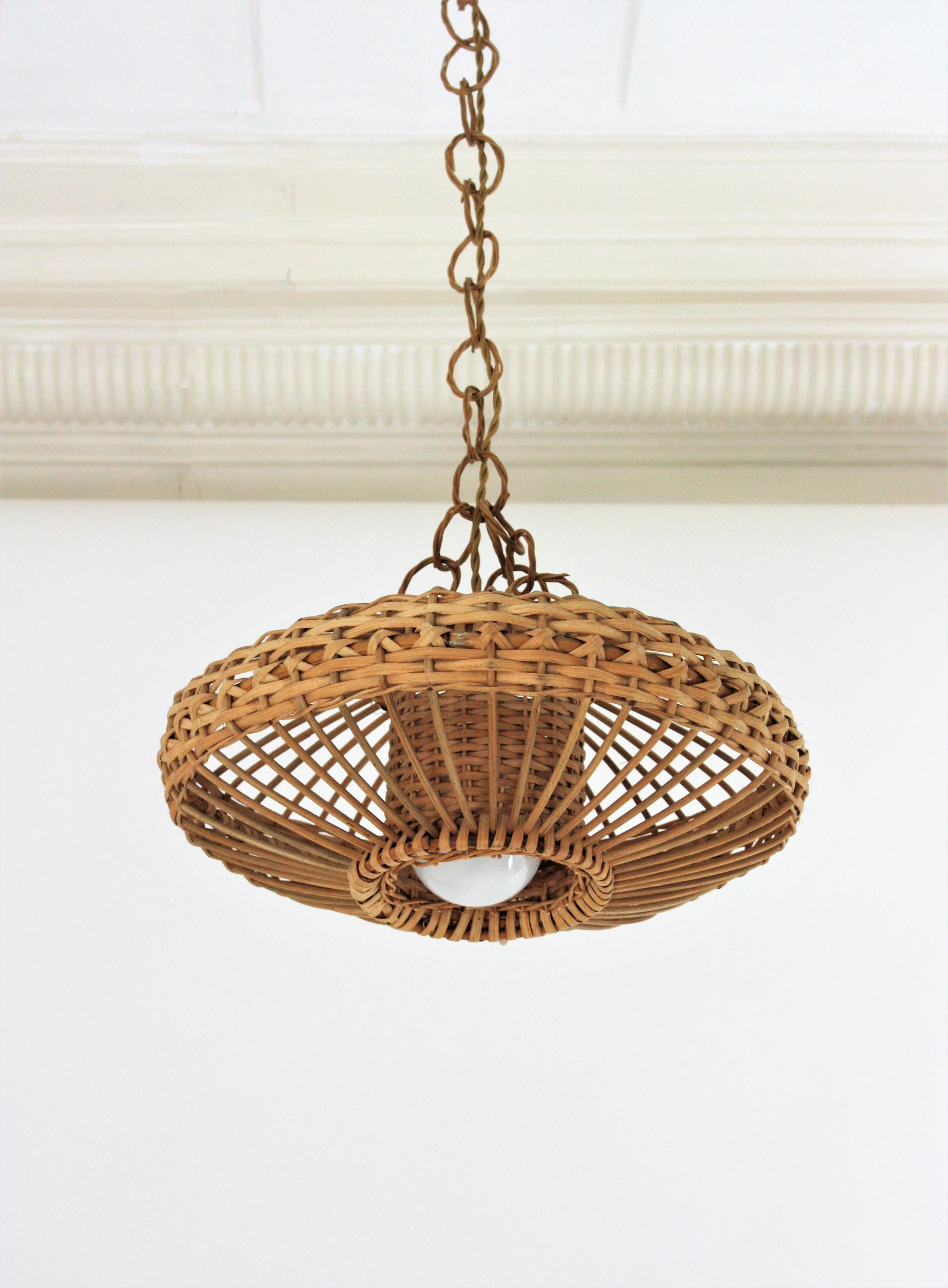 Eye-catching handcrafted braided rattan / wicker pendant hanging lamp. Spain, 1960s.
This beautiful suspension lamp features a woven wicker ufo shaped lampshade with an inner cylinder lampshade. It hangs from a chain with braided rattan links ended
