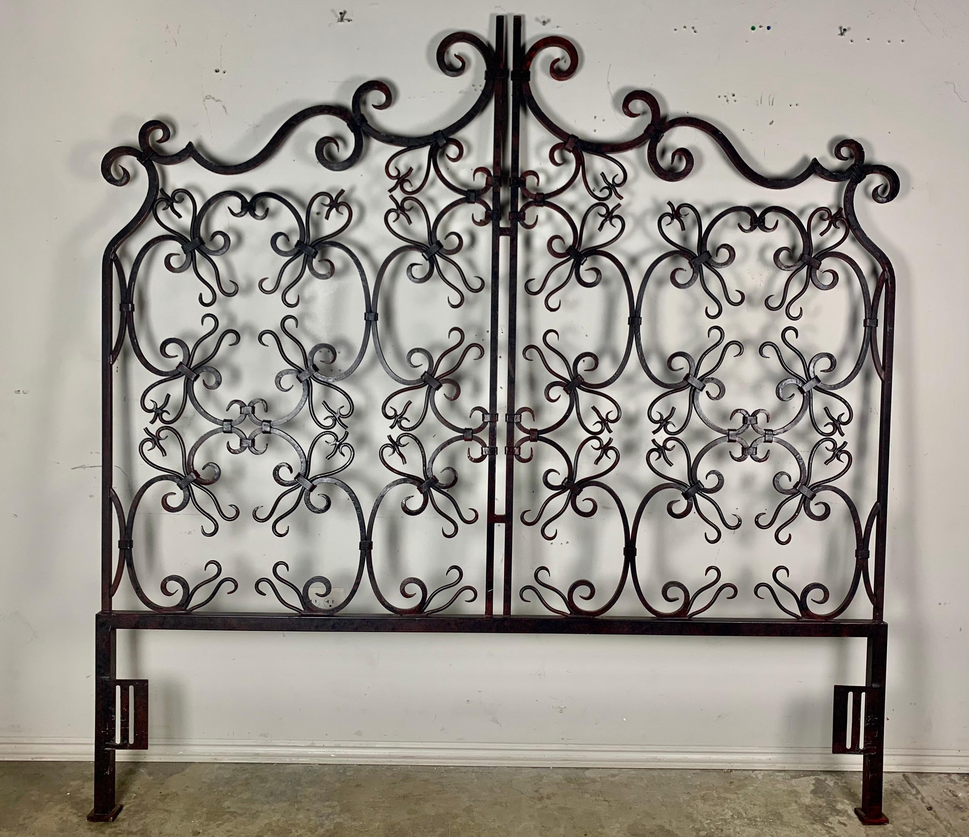 Monumental Spanish hand wrought iron king size headboard with beautiful scrolled patterns throughout. The iron has developed a beautiful patina over the years.
