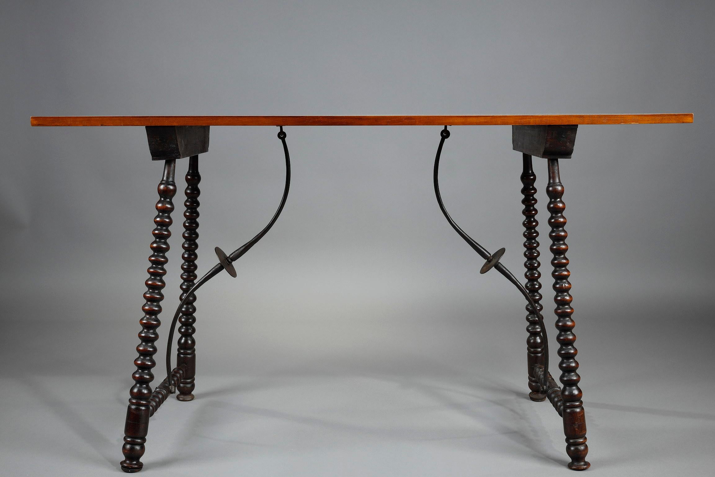 Console in the Spanish high period style in walnut veneer resting on oak legs carved in rosary. The whole is connected by wrought iron crosspieces, with elegant and sinuous lines, decorated with discs. Taking up classic forms, the console fits