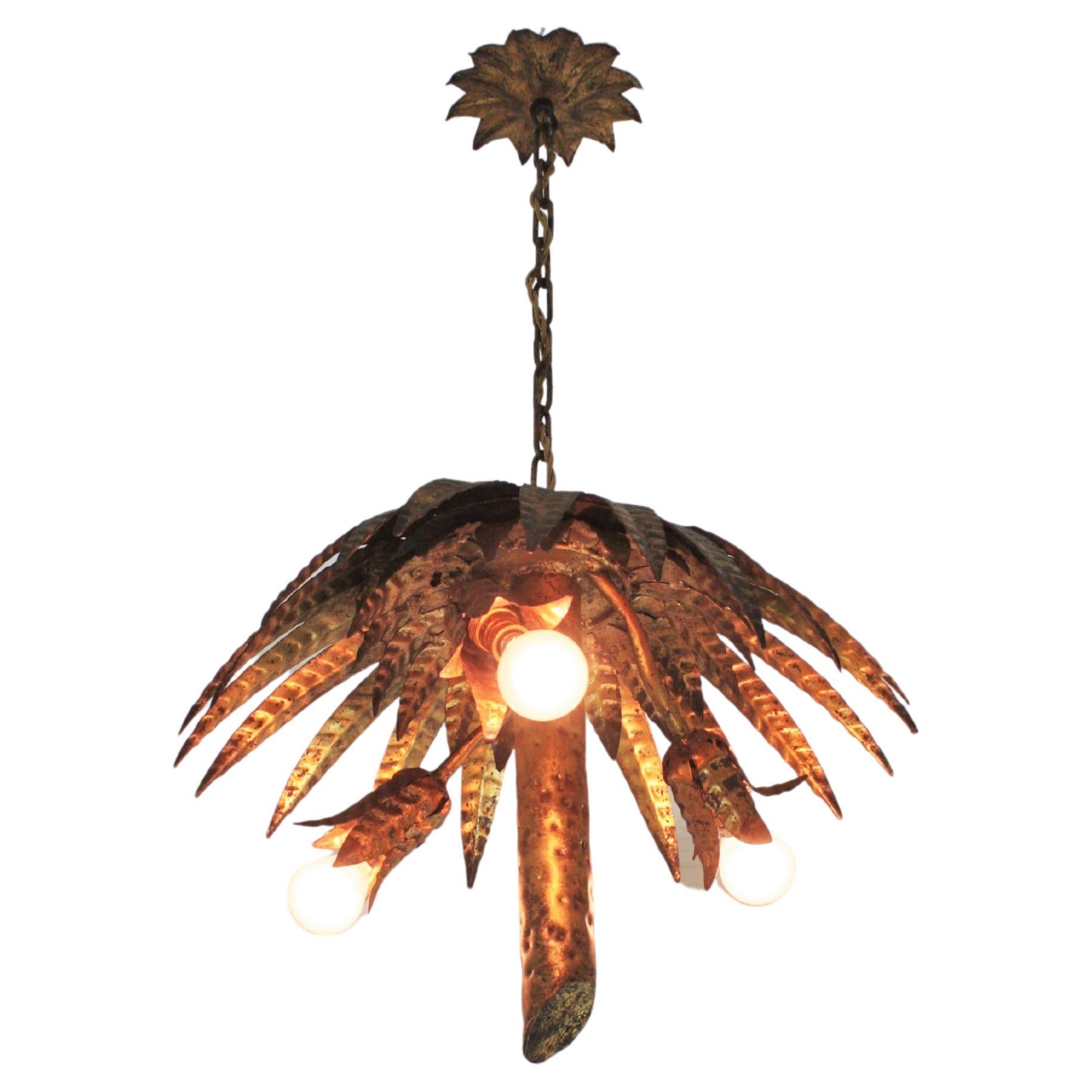 Hollywood Regency Palm Tree Pendant Light, Gilt Iron, Gold Leaf
Eye-catching hand-hammered gilt iron palm tree ceiling light fixture or pendant. Spain, 1950s.
This ceiling lamp is entirely made by hand. Featuring has two layers of leaves as a palm