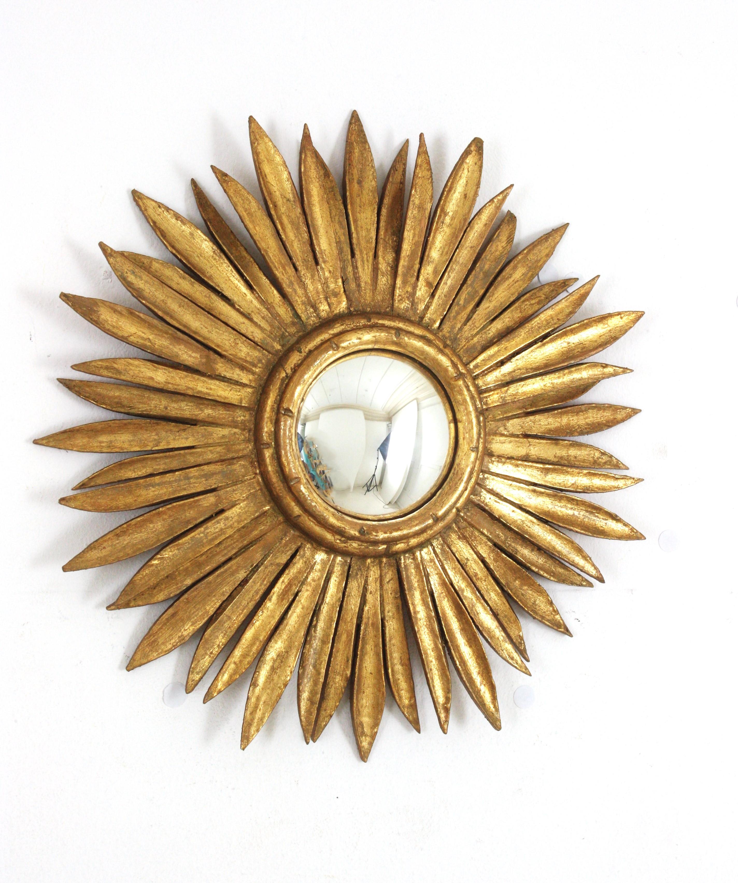 Magnifique miroir en bois doré avec verre convexe, Espagne, années 1940-1950
Ce miroir mural en forme de soleil fabriqué au Mid-Century Modern présente un cadre avec des rayons alternés en deux tailles. Un design glamour de style régence