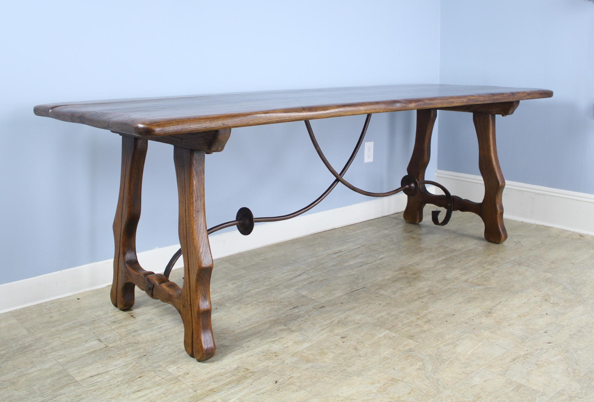 The oak top has been refinished on this interesting iron based table for a clean modern look. Great carved detail and curved iron support underneath. No apron to get in the way so it can seat ten!