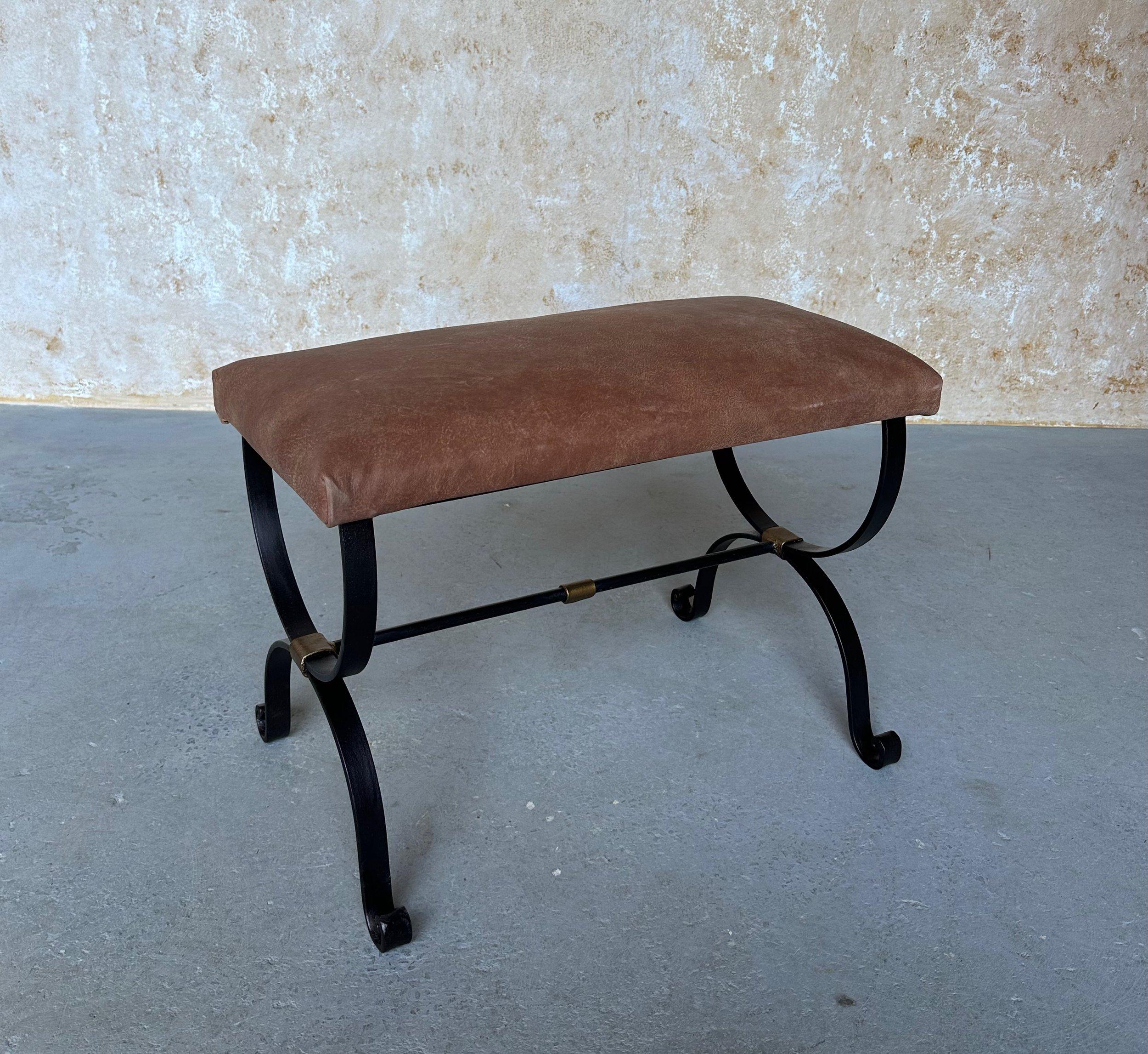 This elegant iron bench was recently crafted by skilled artisans and features scrolled legs and a stretcher with decorative bands that are highlighted in hand-applied gold. Handmade by expert European craftsmen, it has a hand forged iron base with a