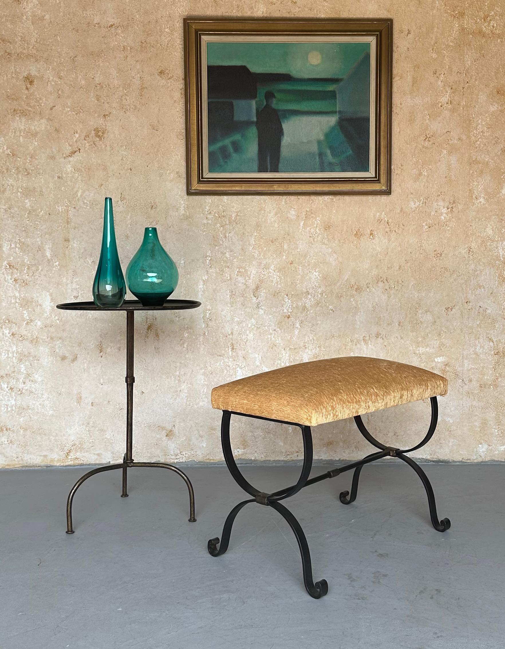This elegant iron bench was recently crafted by skilled artisans and features scrolled legs and a stretcher with decorative bands that are highlighted in hand-applied gold. Handmade by expert European craftsmen, it has a hand forged iron base with a