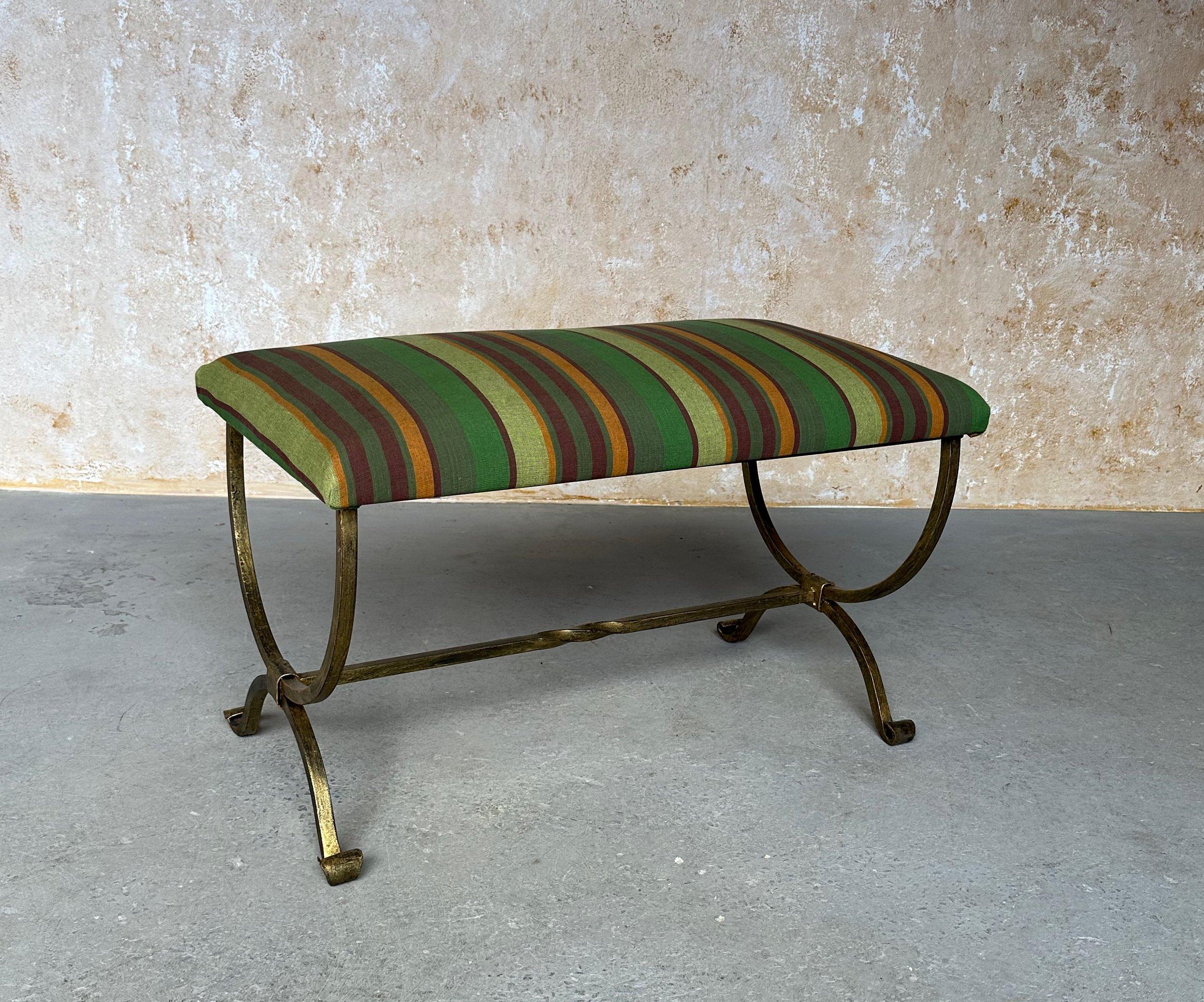 This beautiful Spanish gilt iron bench was recently made by skilled European artisans and features gracefully scrolled legs and a stretcher with a decorative center twist. The hand forged iron base has a rich but subtle gold patinated finish that